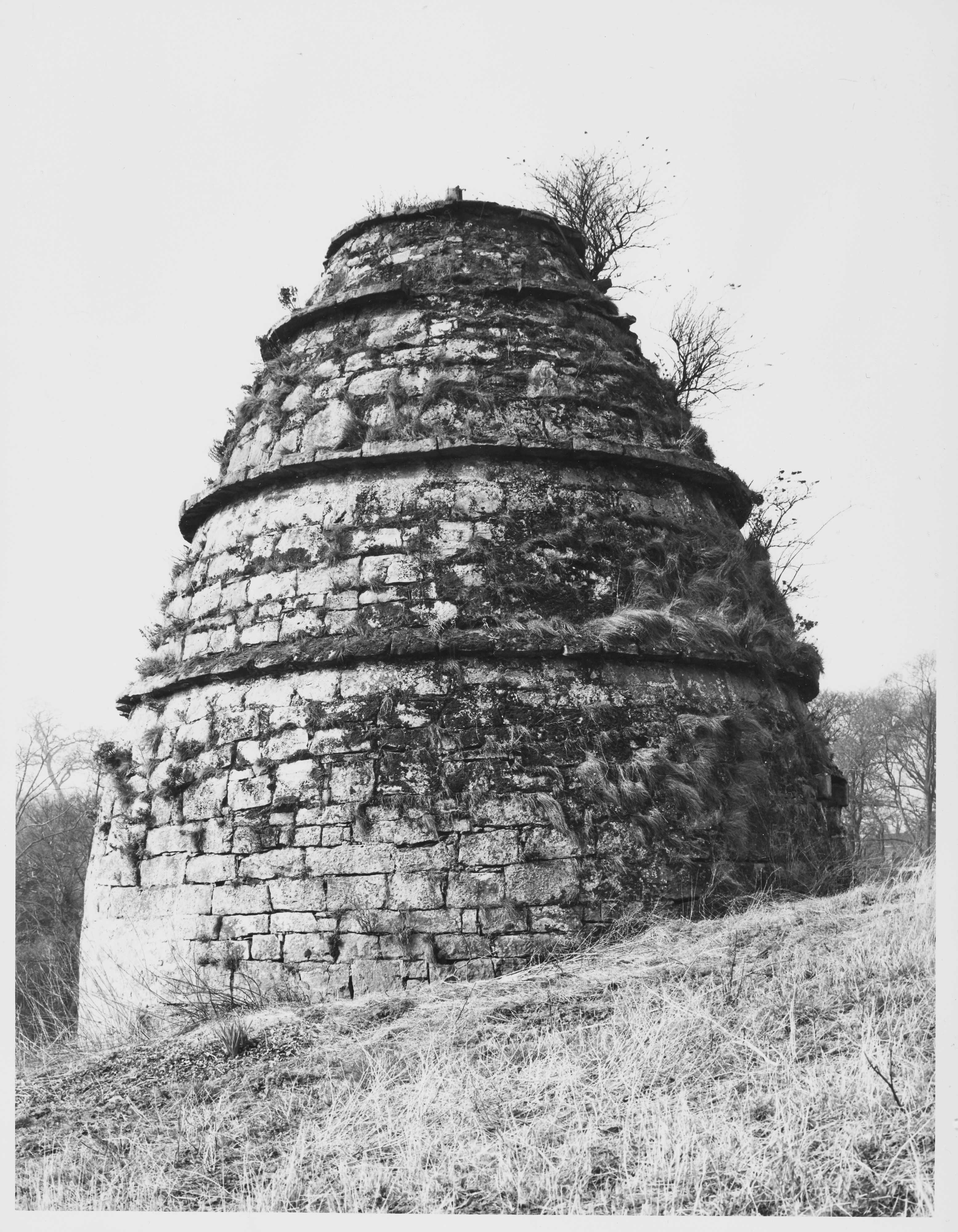 A circular, historic stone doocot with some moss covering the walls