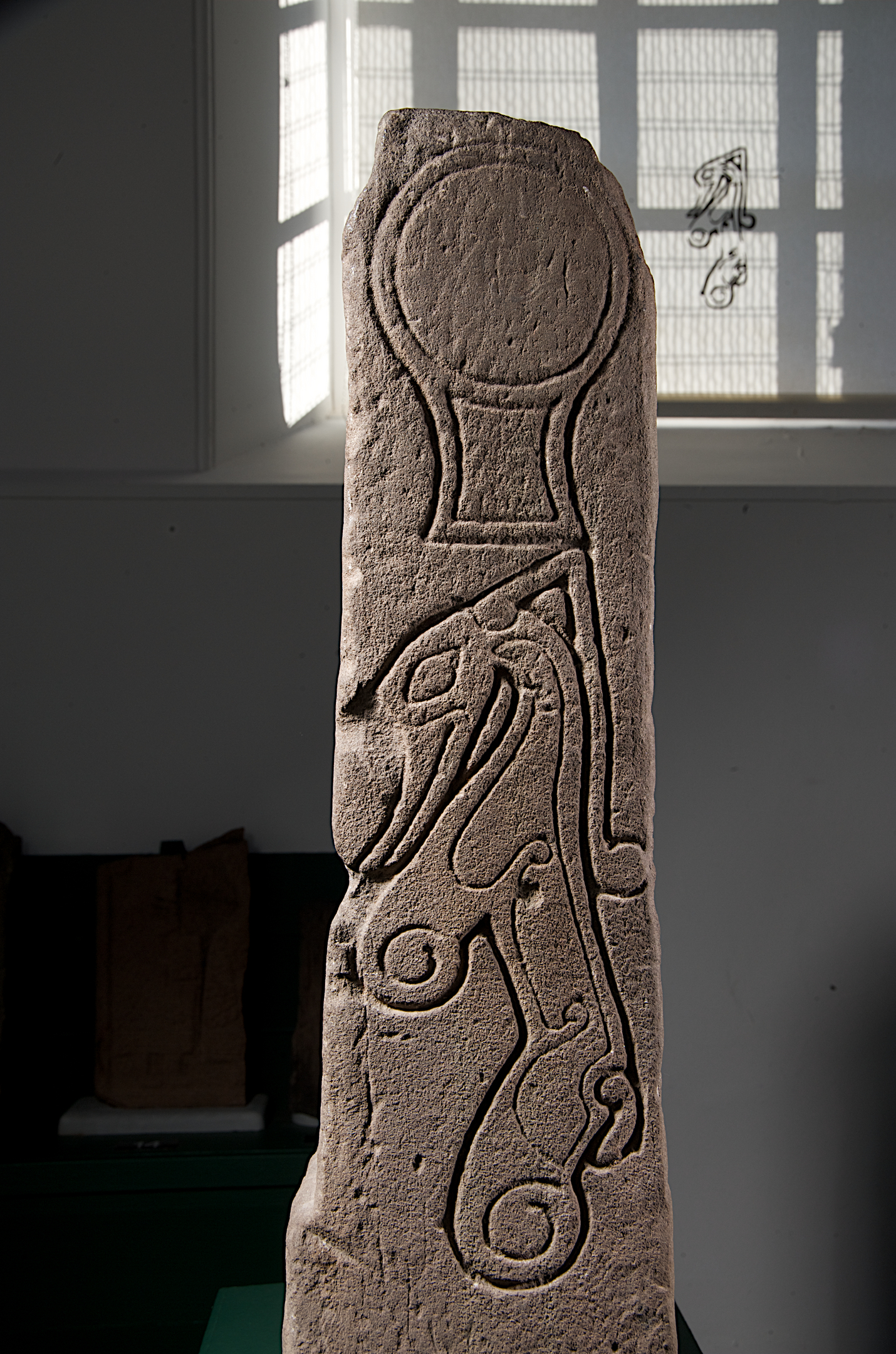 A tall sculptured stone with circle above possible creature
