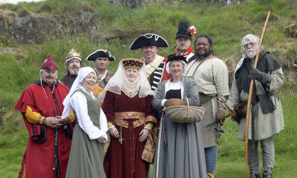 A group of costumed performers posing for a picture on a grassy hill