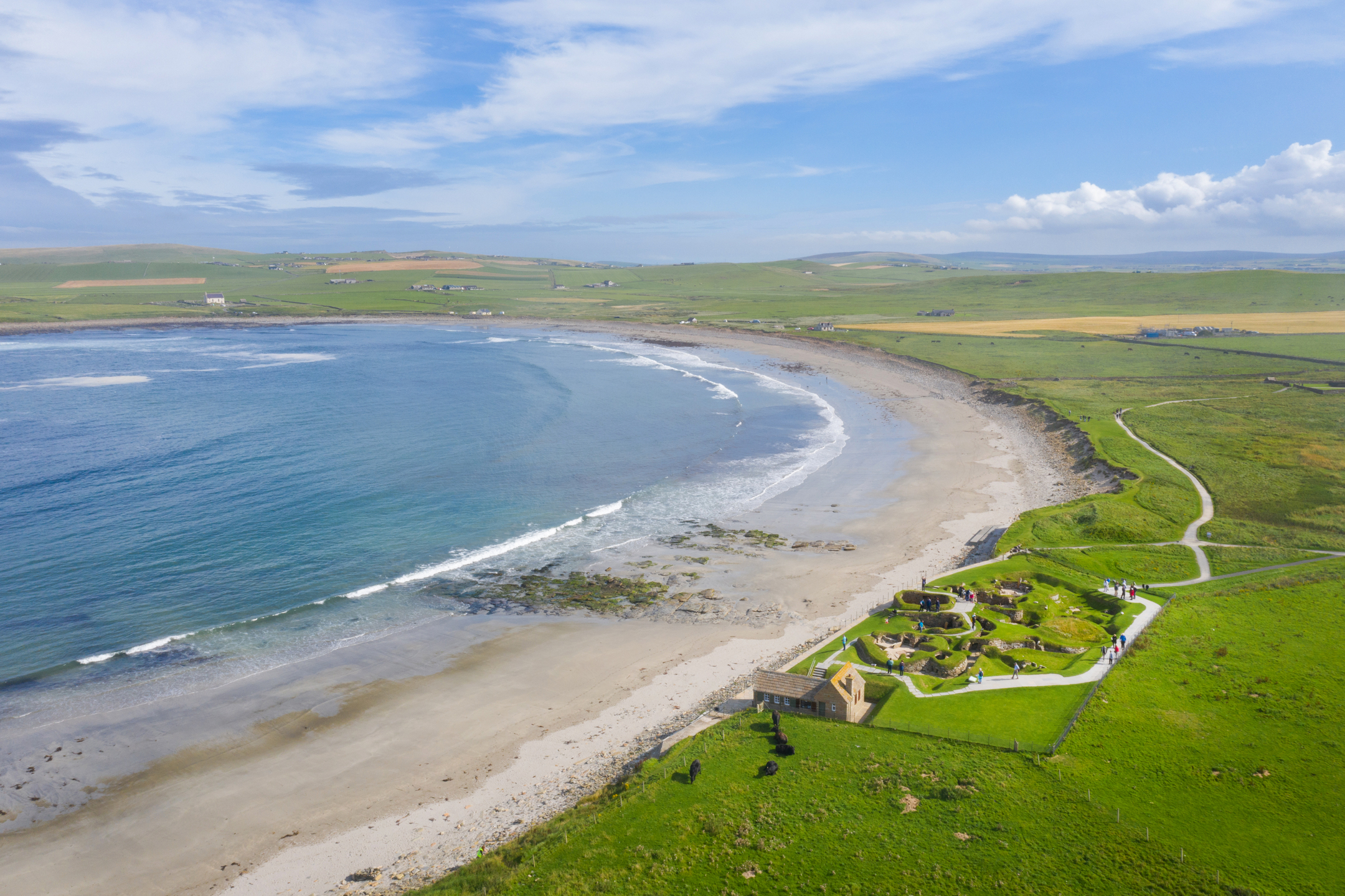 Aerial view looking at Skara Brae and the sea on a sunny day