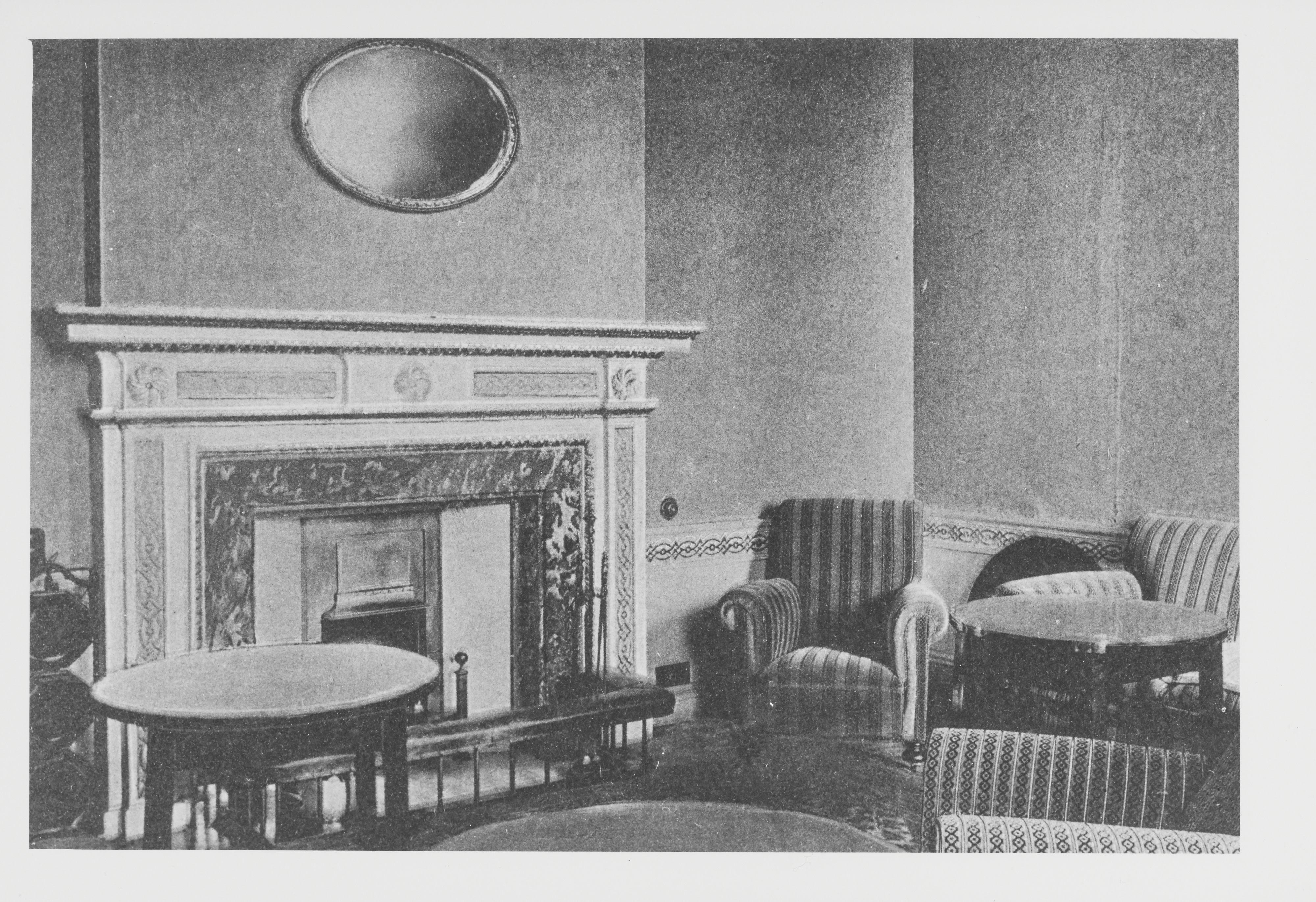 Black and white photo of a public room with chairs and tables and a fireplace