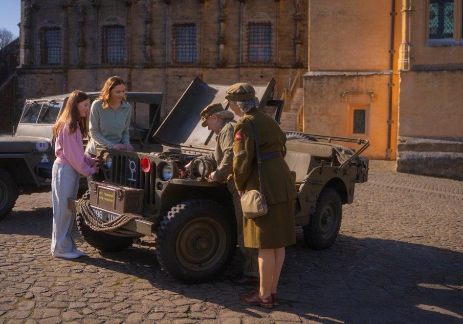 A family standing next to a reenactor at a wartime car.