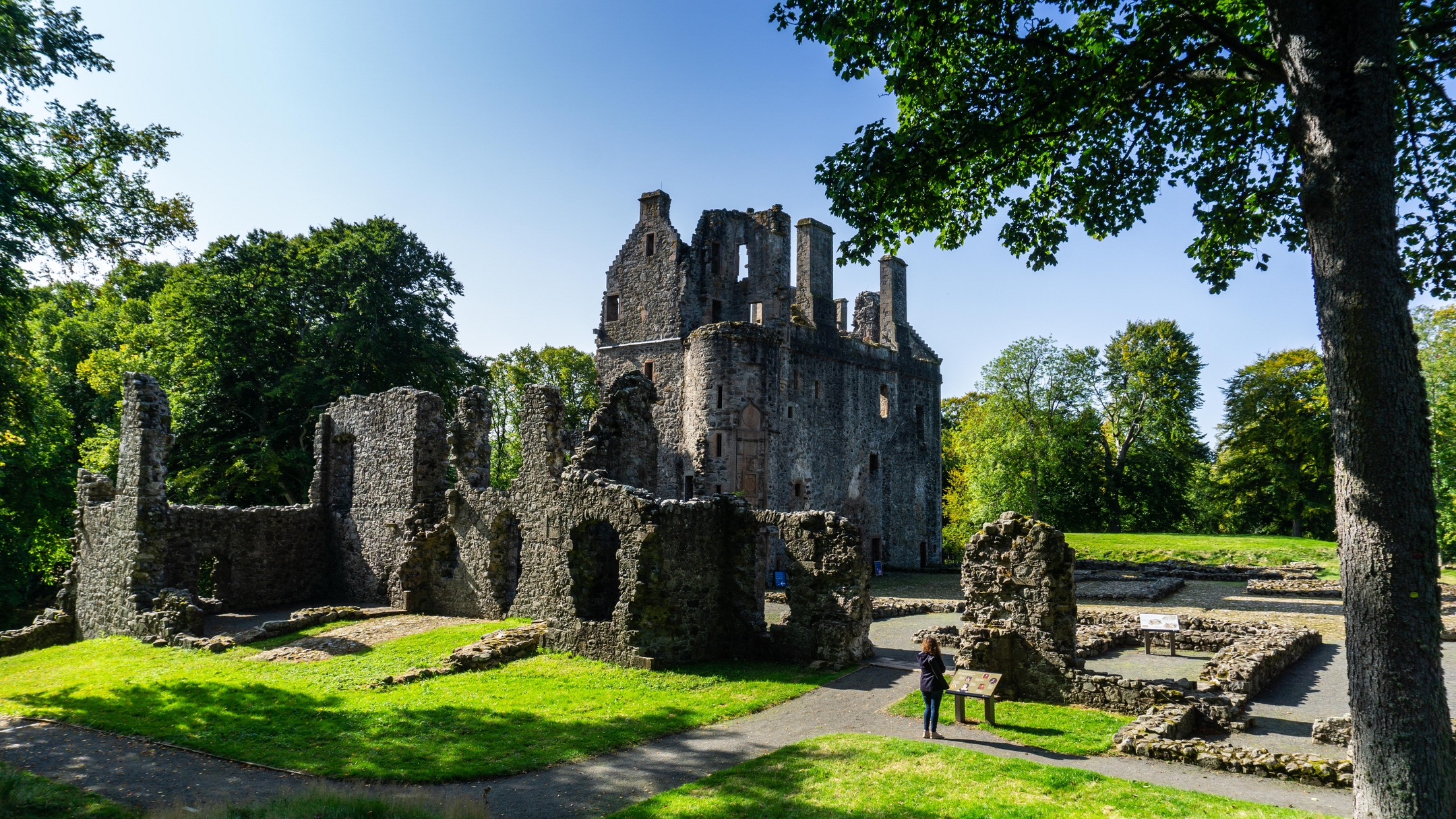 Castle ruins with areas of varying heights and trees around the outside