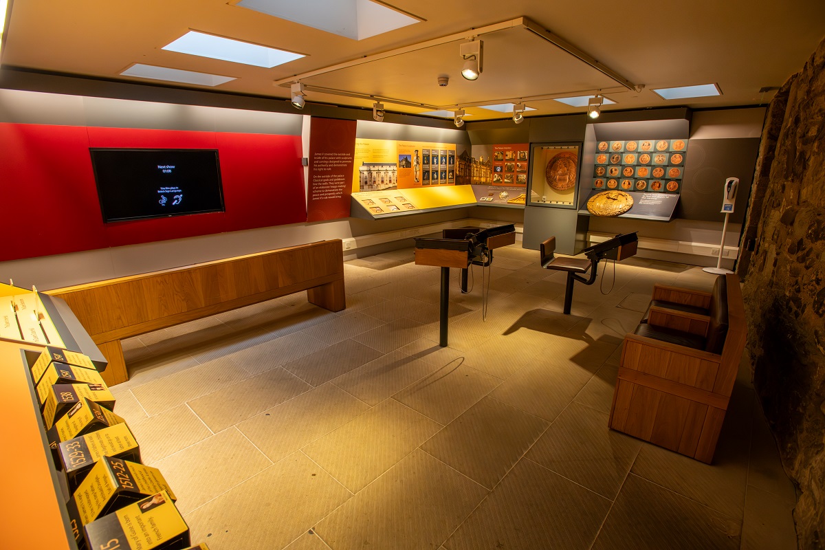 A room filled with object exhibits, exhibition panels and a large screen