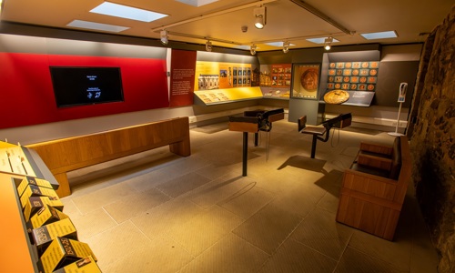 A room filled with object exhibits, exhibition panels and a large screen