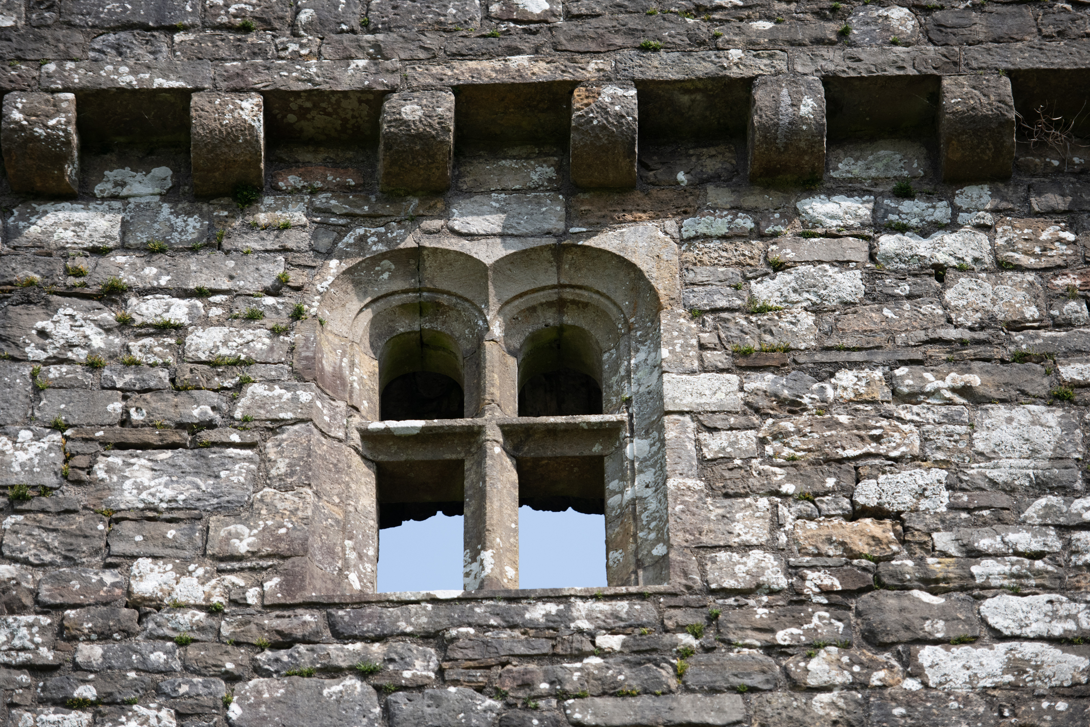 Close-up of a medieval stone window with carved arches at Hermitage Castle