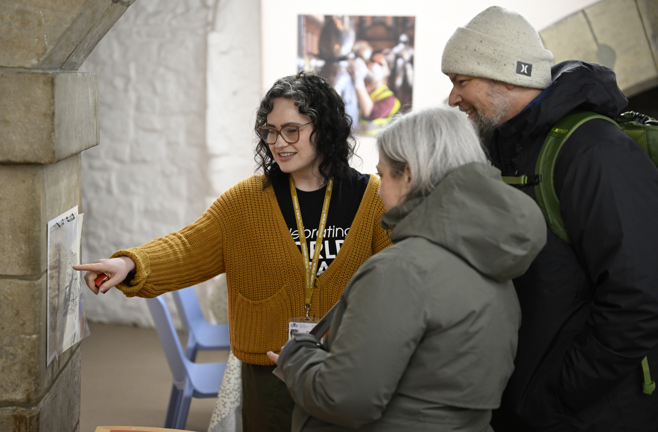 Woman from Historic Environment Scotland pointing at a map of the Edinburgh Old Town with two visitors to Edinburgh Castle 