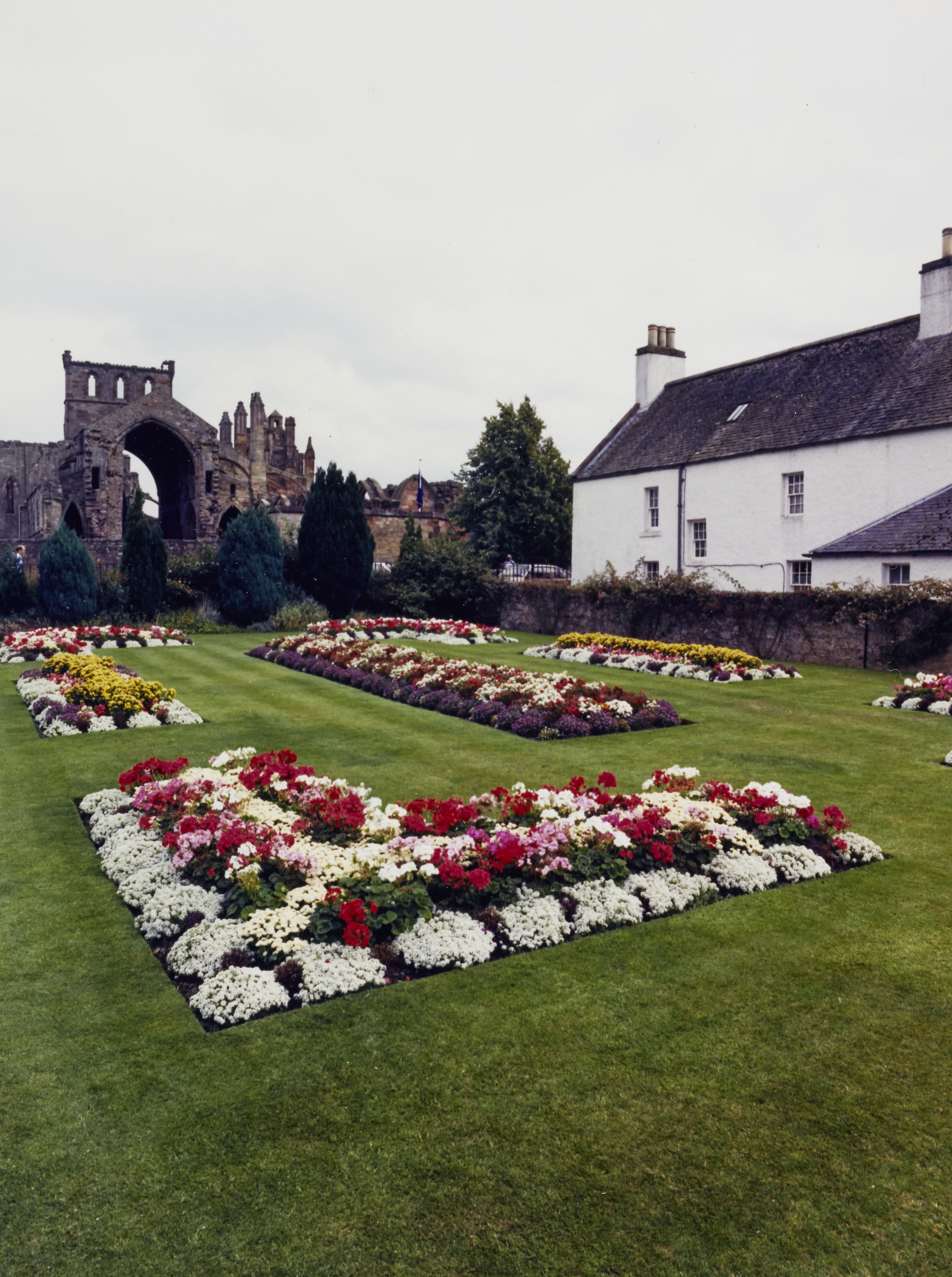 Flower beds in the foreground and Melrose Abbey beyond