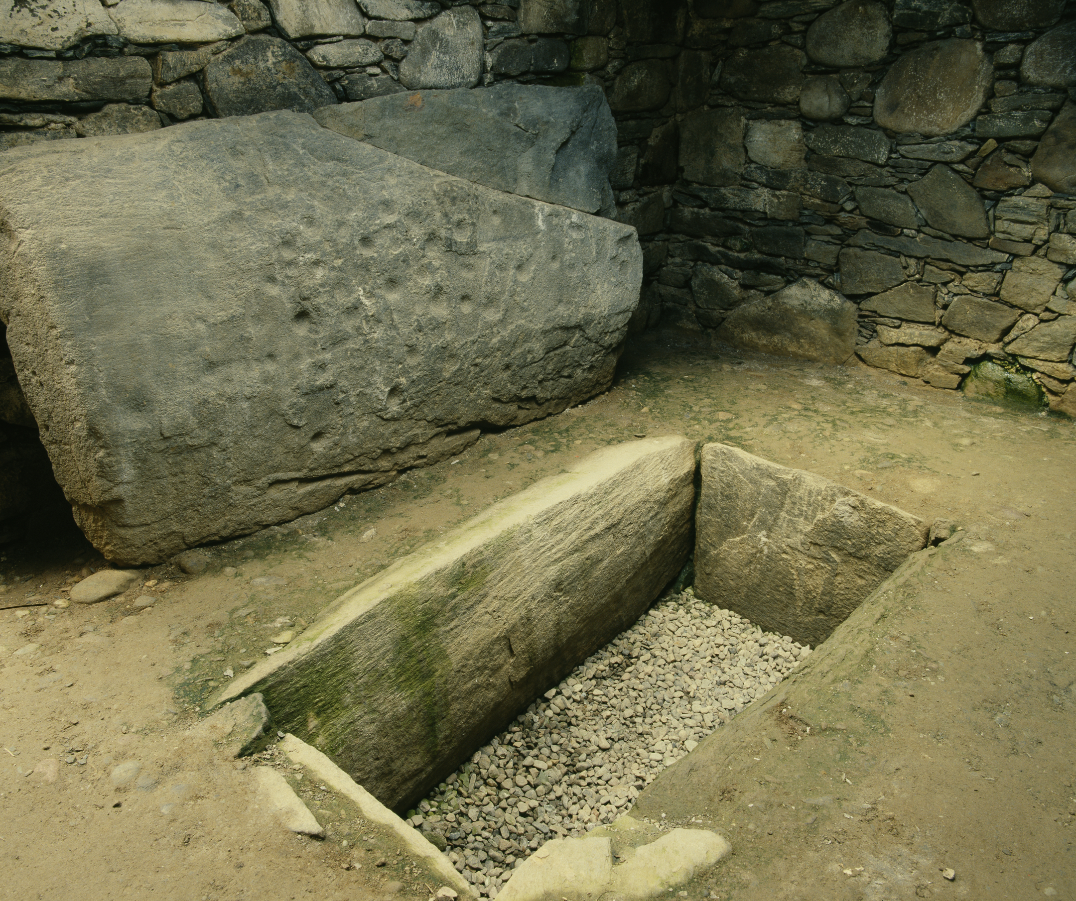Stone walls and a stone slab with a rectangular hole in the ground
