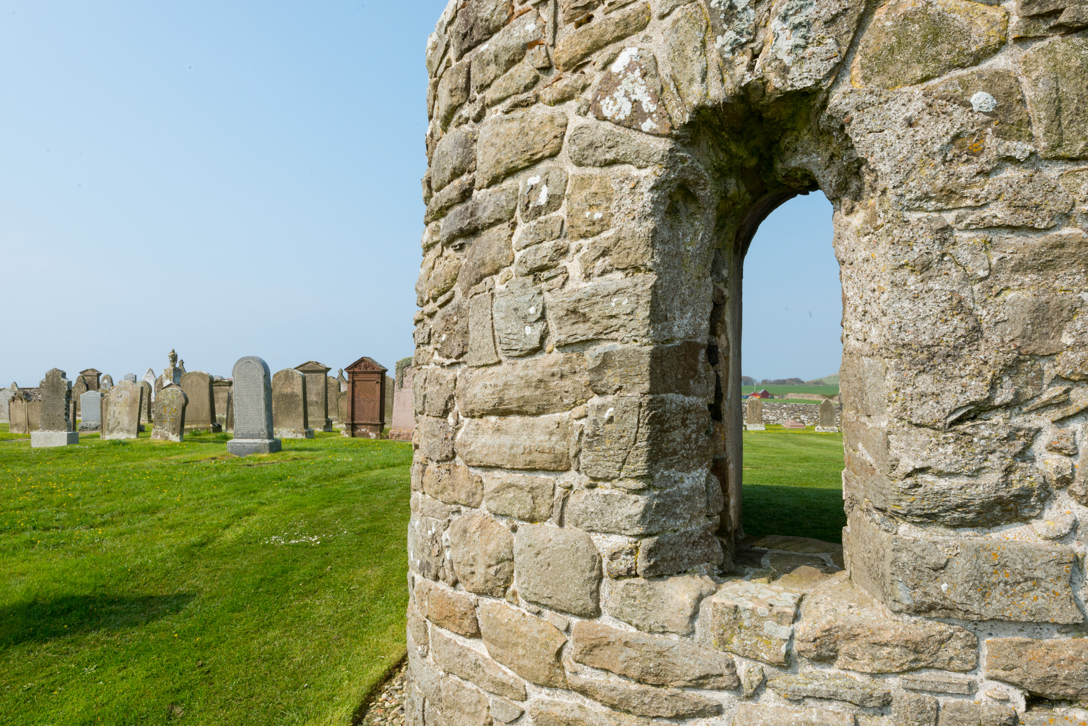 Remains of church with space for window and gravestones in the background