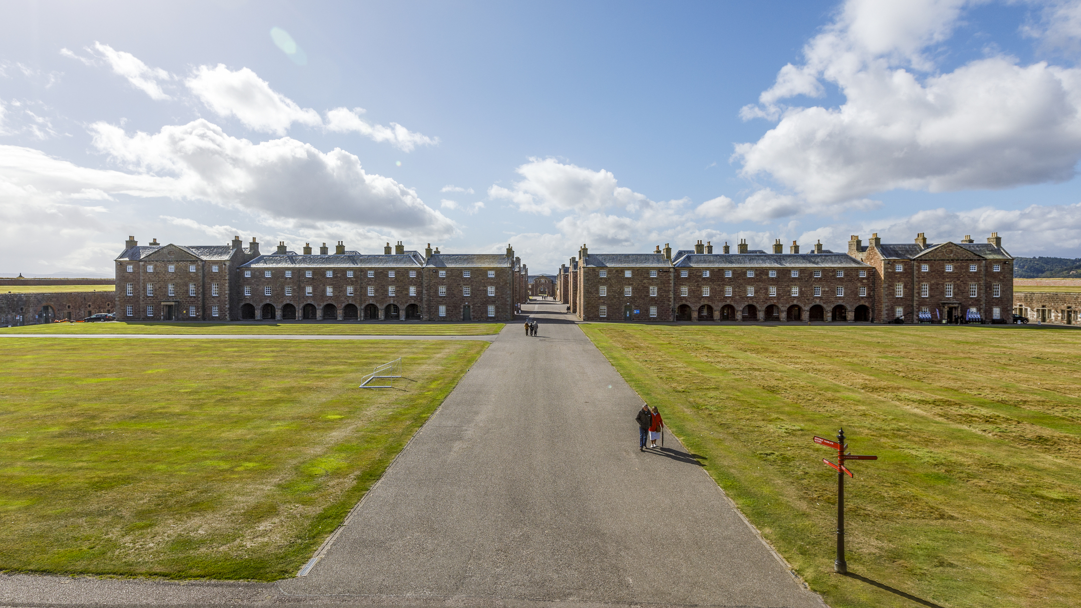 A straight pathway runs through the centre of Fort George’s large grassy parade ground, flanked by long rows of barrack buildings.