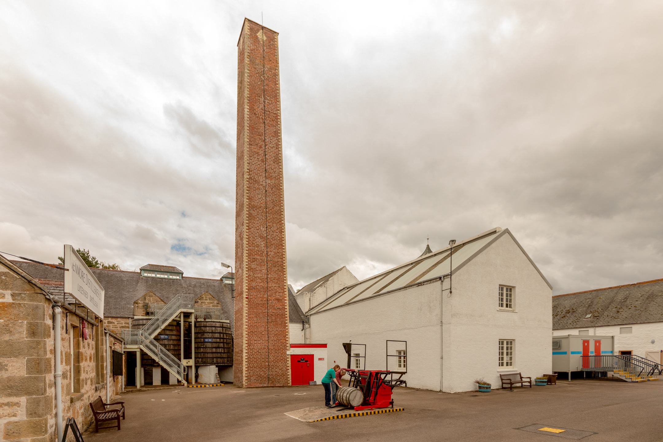 Courtyard at Dallas Dhu distillery featuring a prominent red-brick chimney.