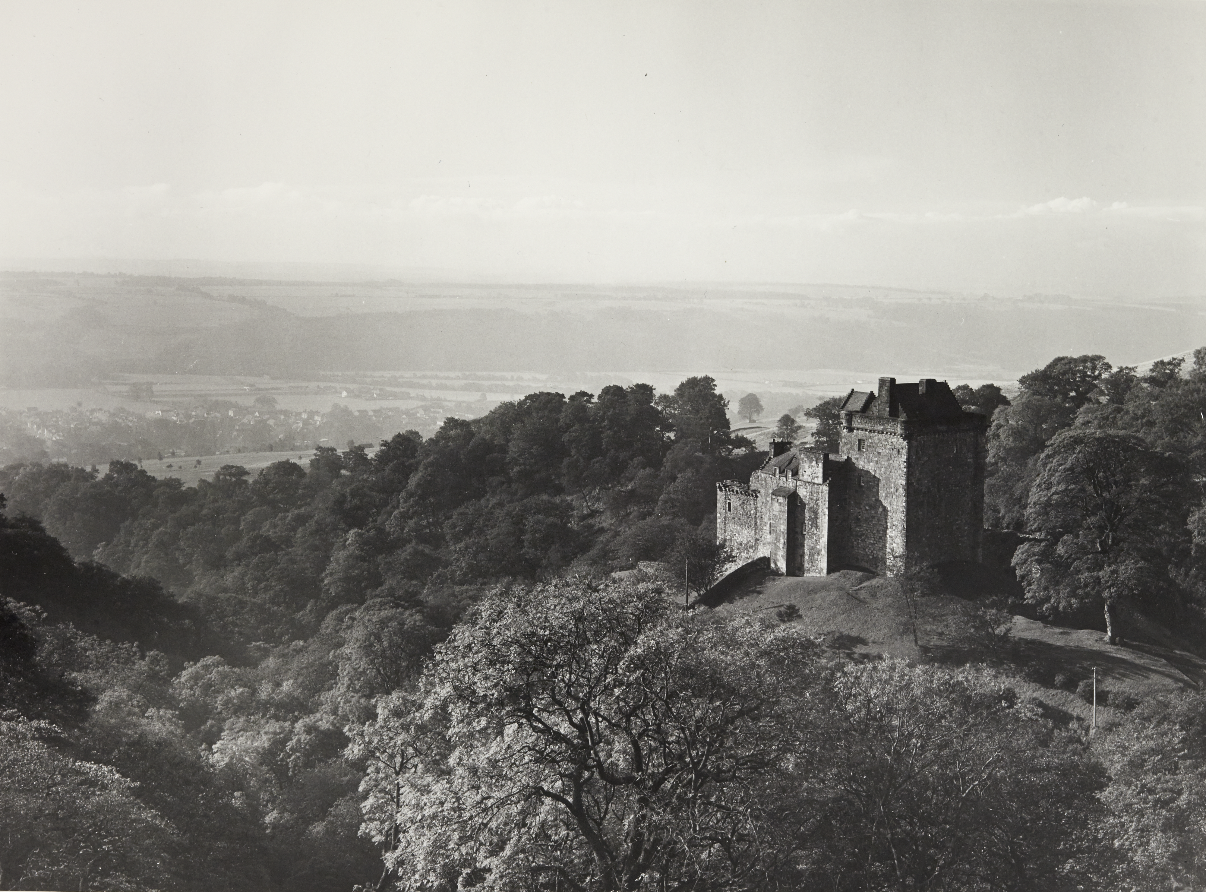 Black and white photo from above and near Castle Campbell, showing the castle in its hillside setting and the vast countryside beyond