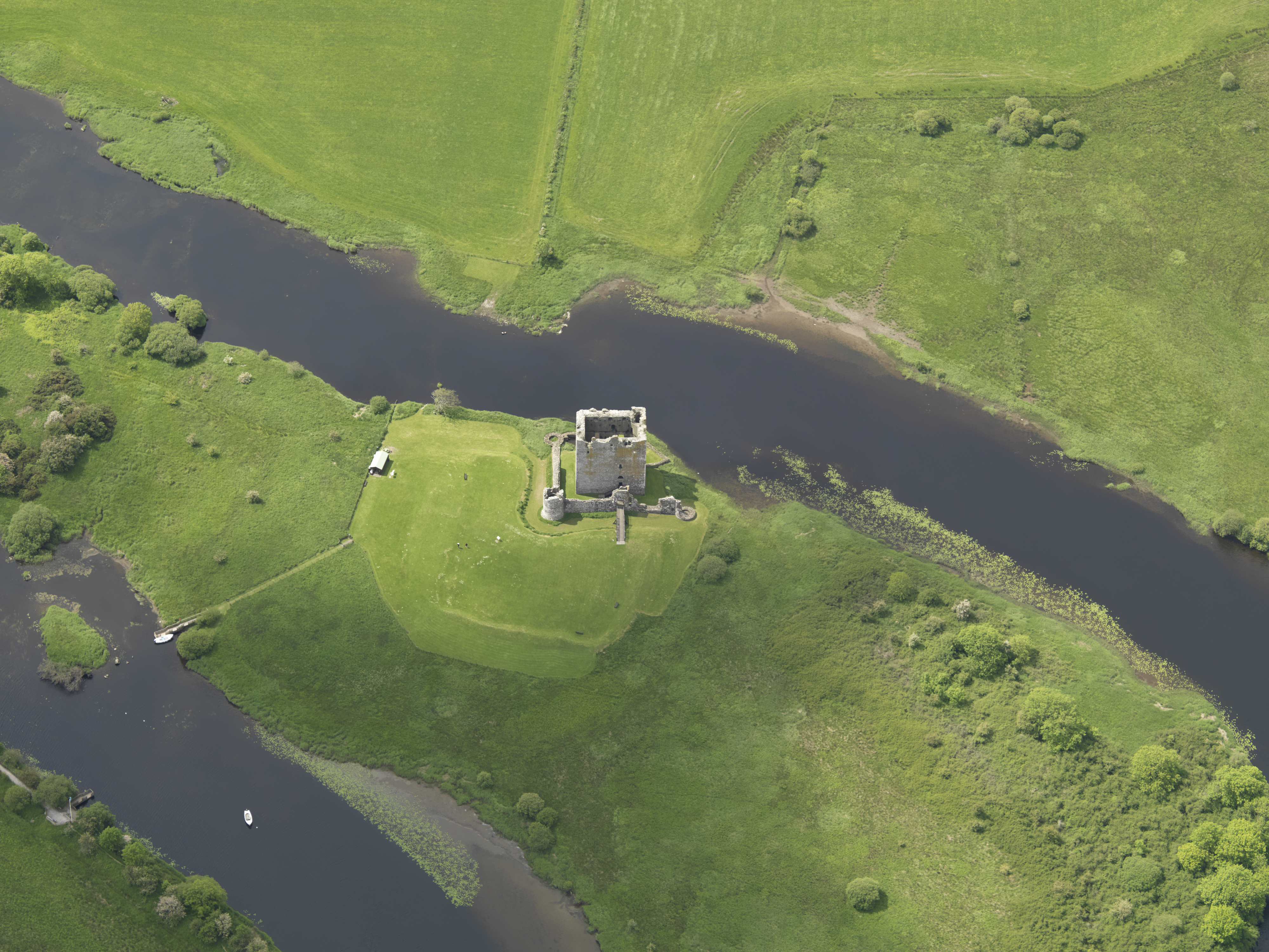 Aerial view of castle with river on both sides and otherwise very green surroundings
