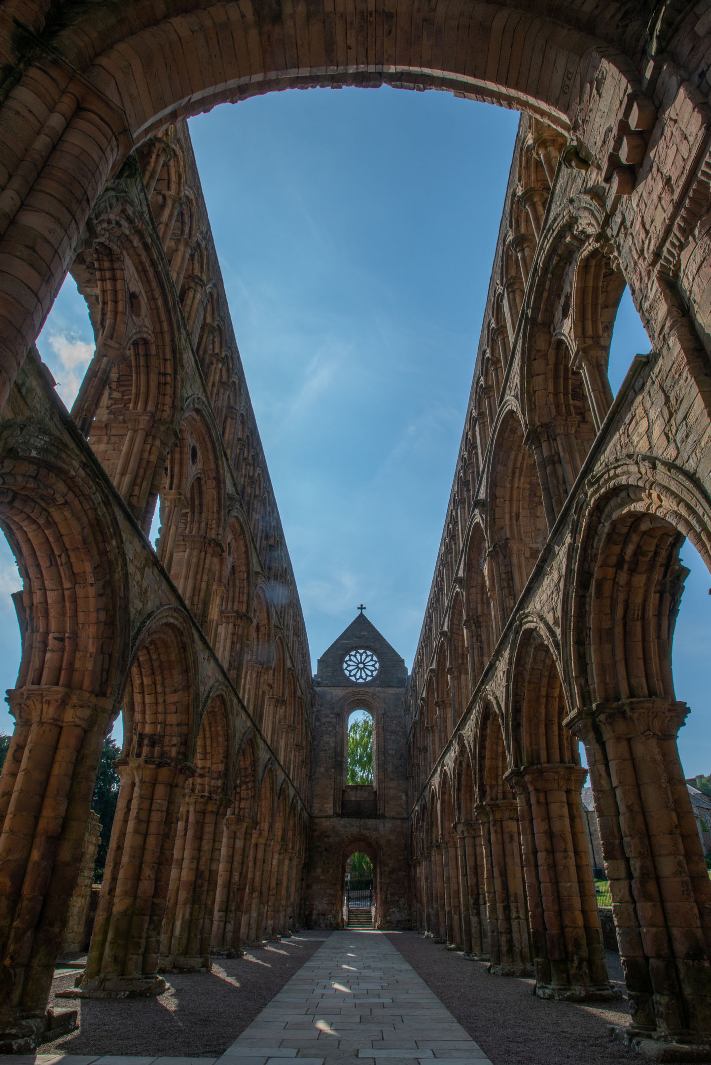 Tall stone nave with pointed arches and clear sky visible through roofless structure.