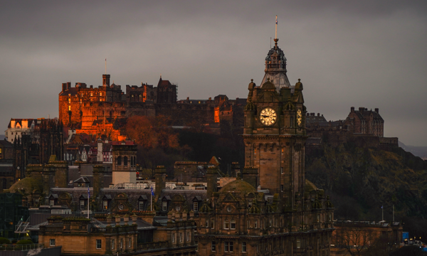 A distant photo of the outside of Edinburgh Castle is shown as it begins to get dark