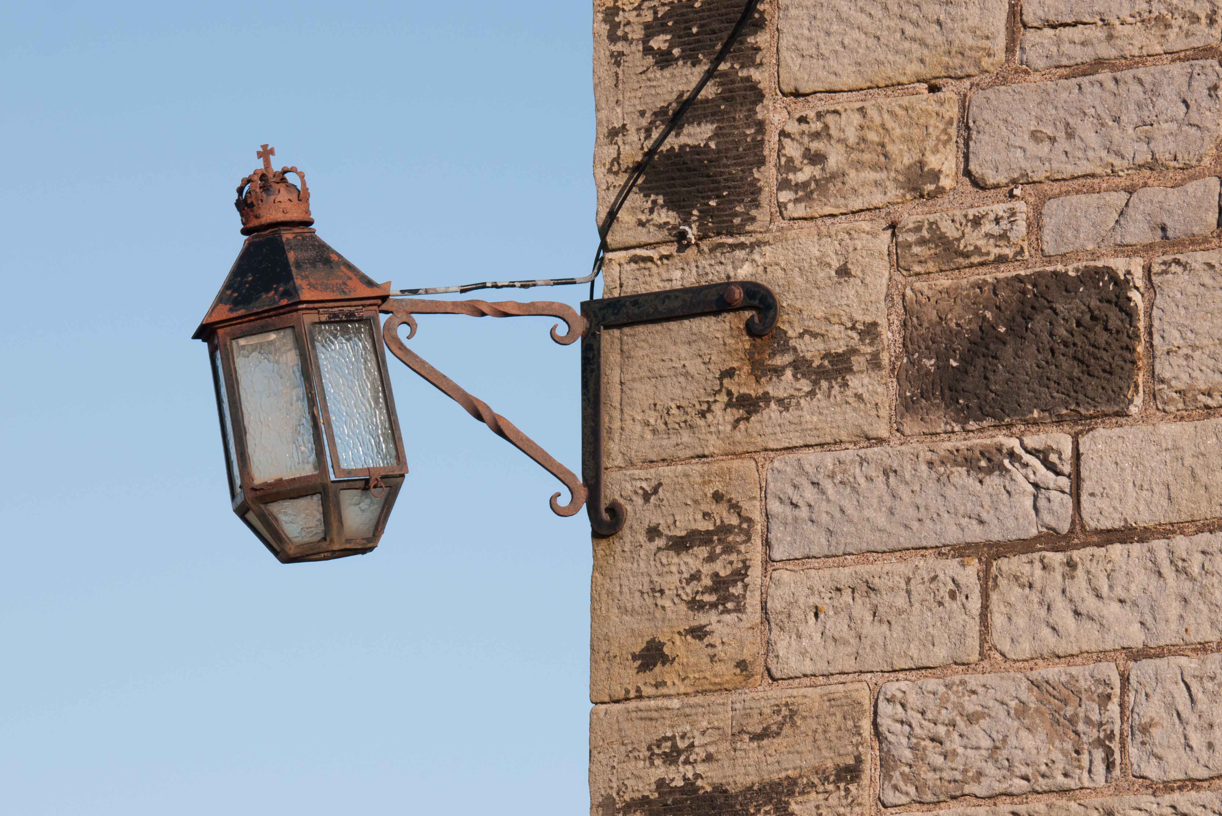 A black iron lantern fixed to a stone castle wall