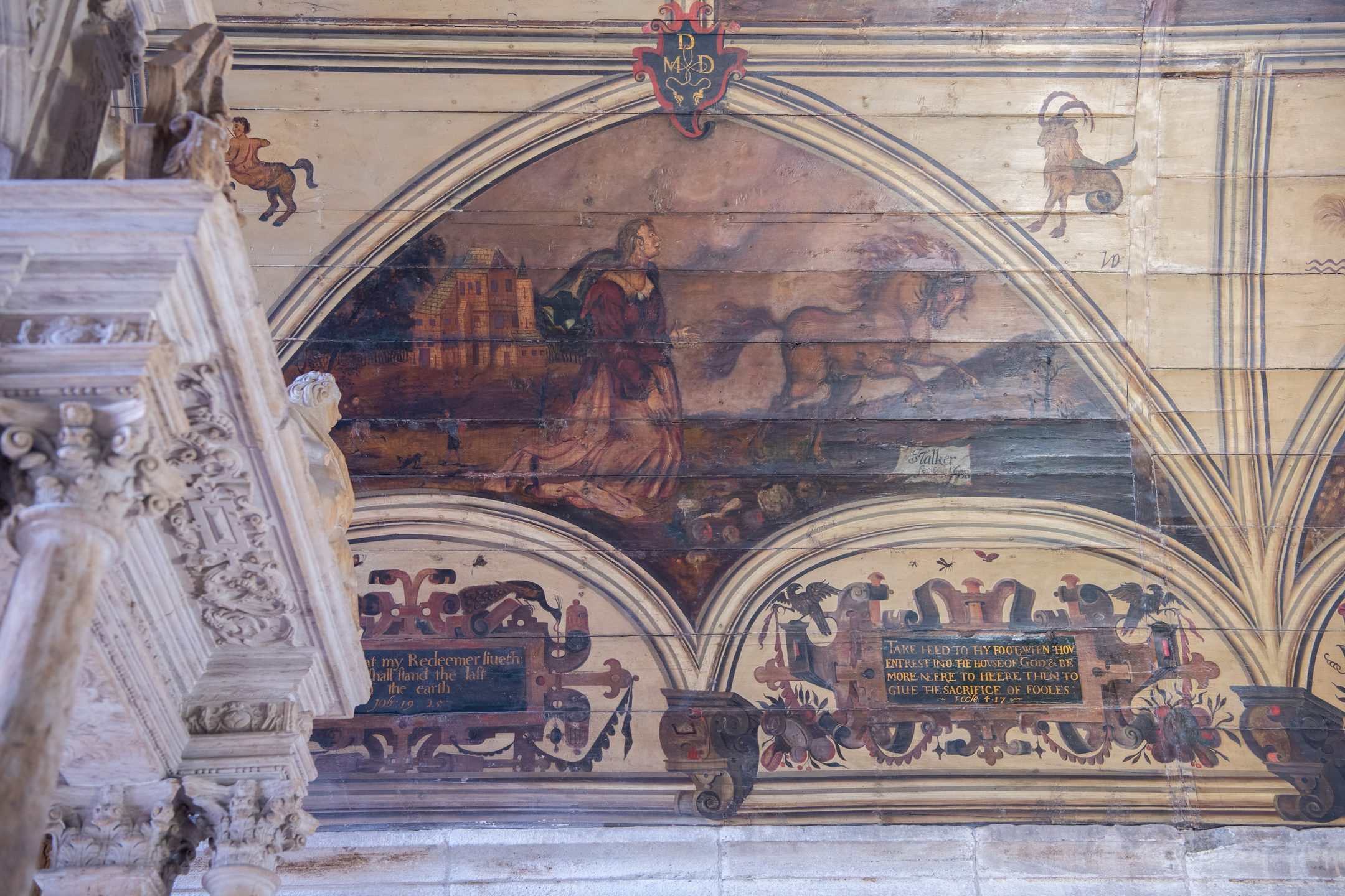 Historic ceiling painting depicting two small, child‑like figures seated back‑to‑back, each holding a small object, with the Roman numeral II beneath them on aged wooden panels.