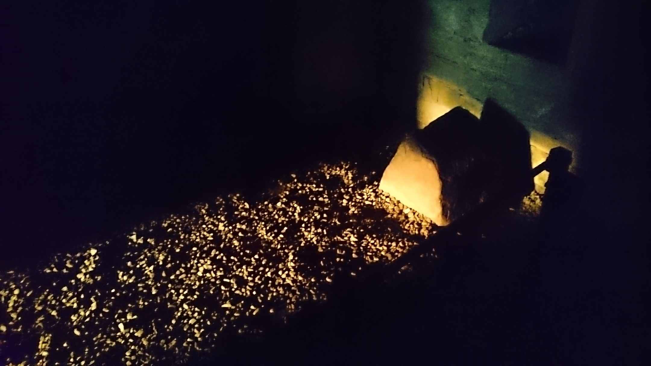 Sunset shining on a bit of a room with stone and a gravel path.