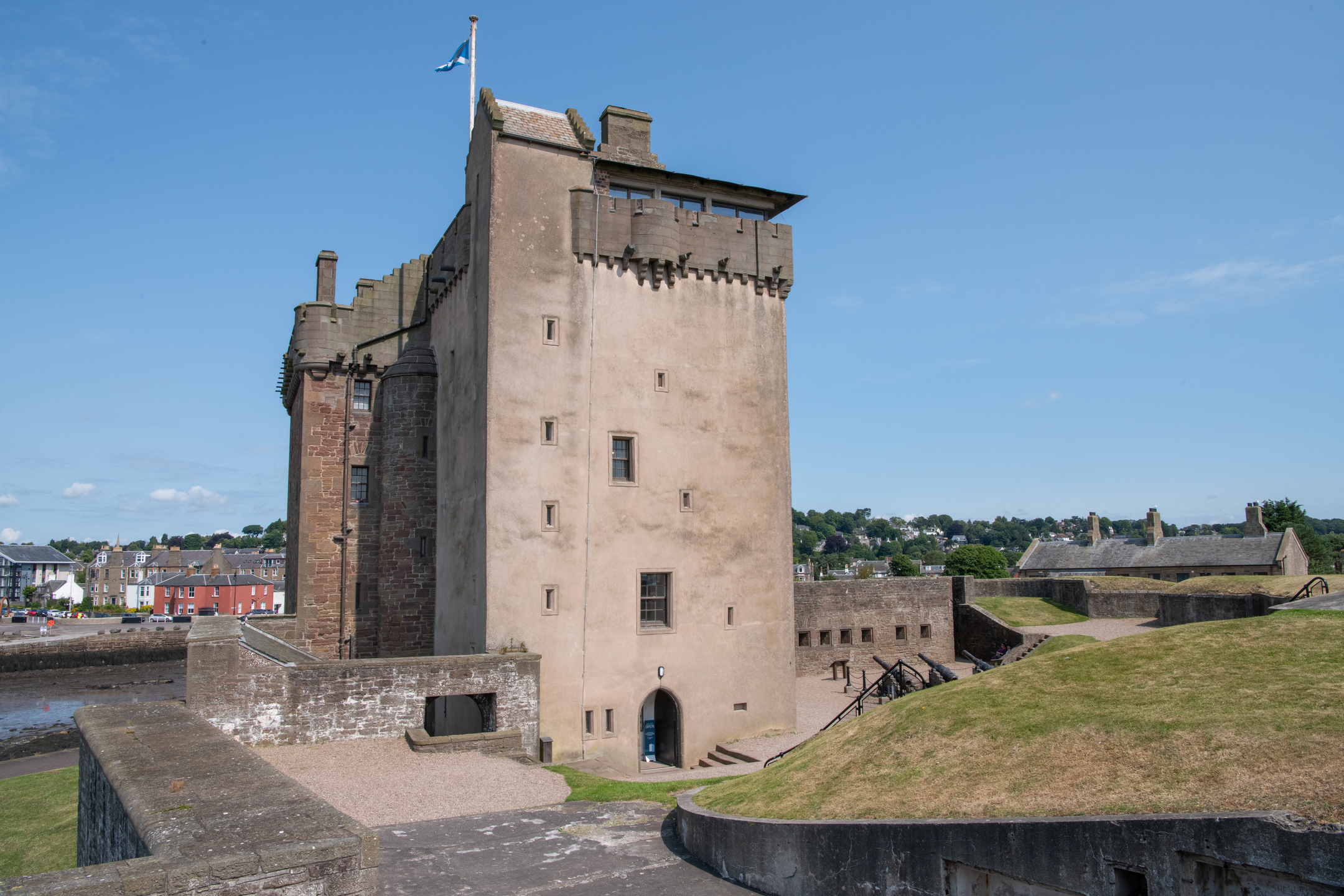 Close view of the main tower of Broughty Castle with stone walls and small windows, set against a bright blue sky
