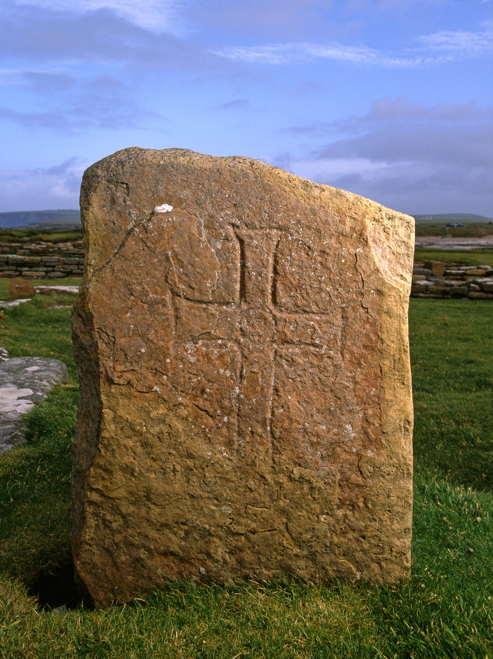 A weathered standing stone carved with a simple cross design.