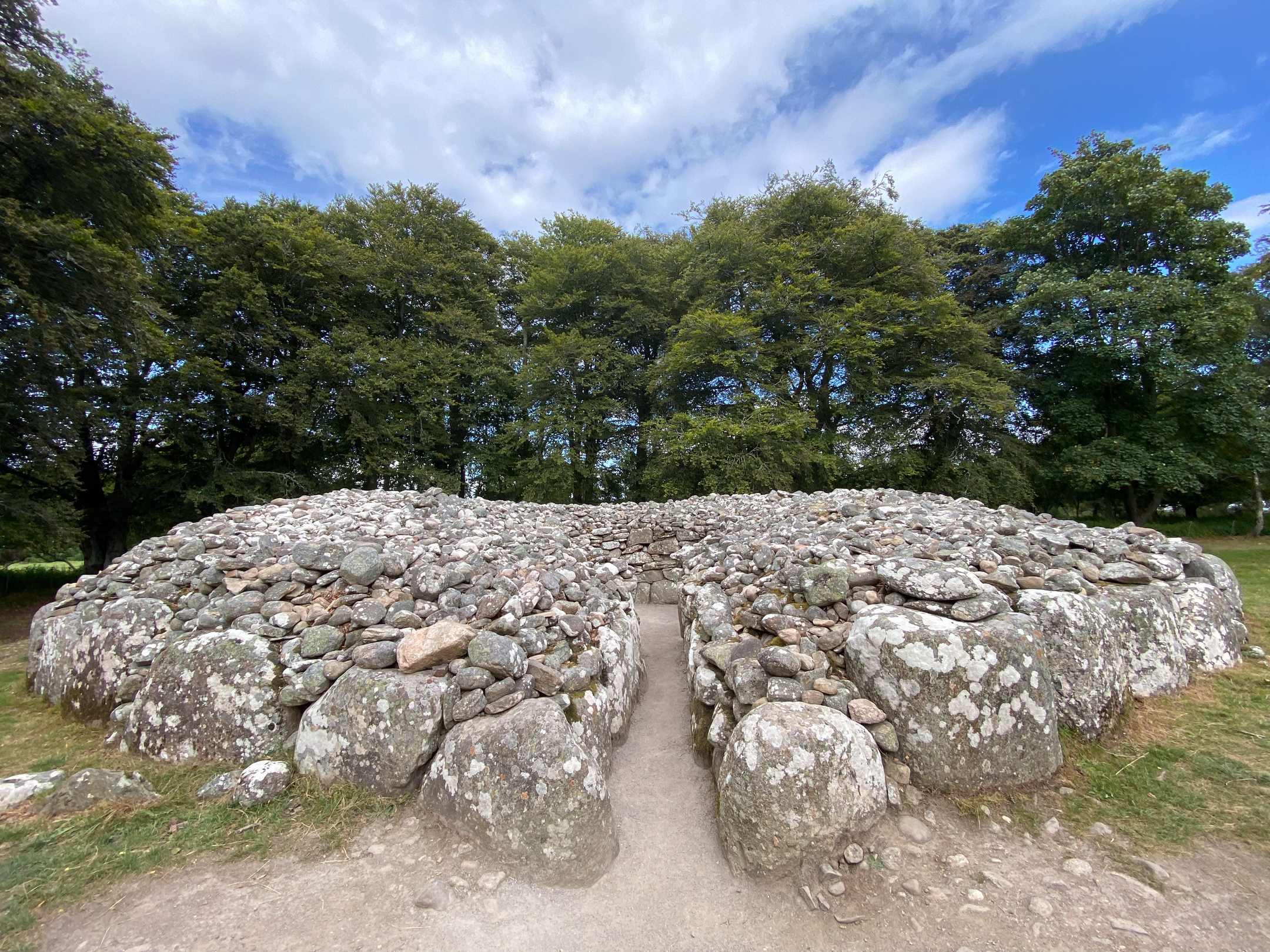 Facing the entrance of a cairn, trees behind