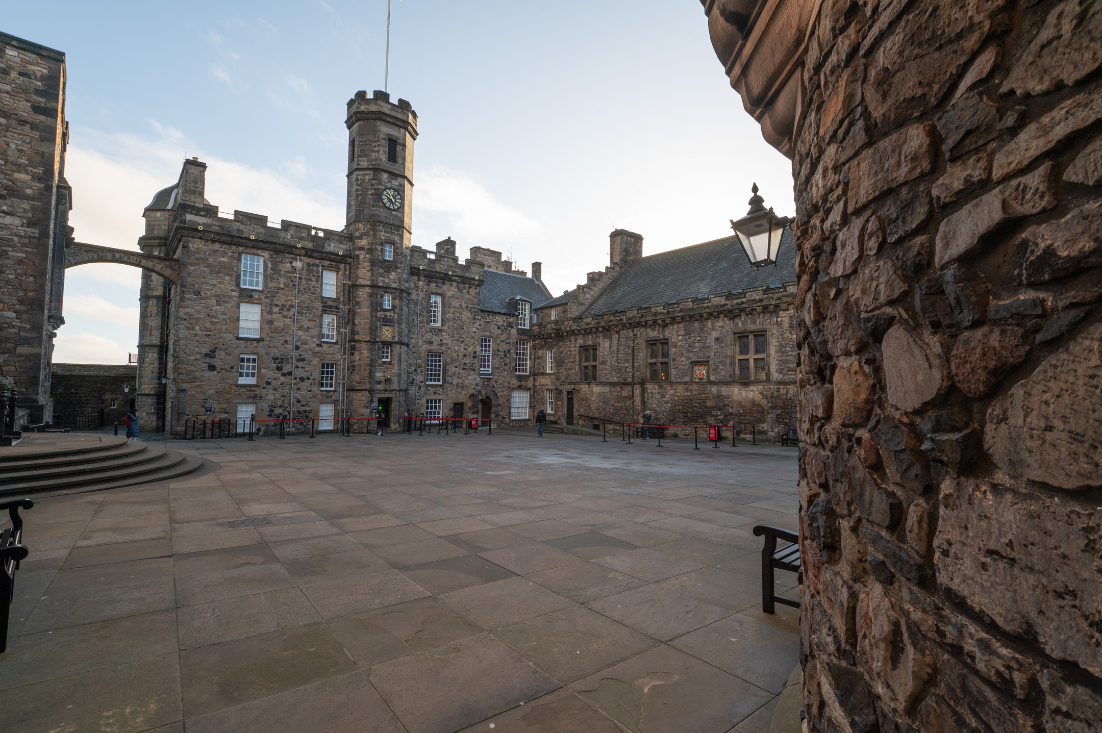 Open stone courtyard inside Edinburgh Castle, surrounded by historic stone buildings and a central clock tower.