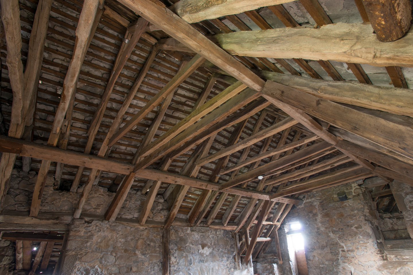 An old ceiling, with stone walls and wooden beams securing the building. 