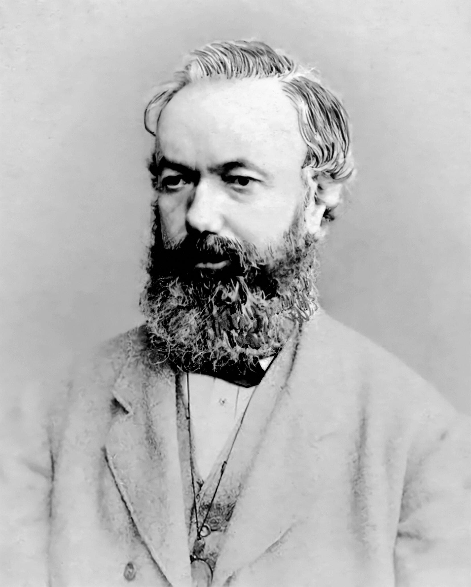 Black and white portrait photograph of a person. They are wearing a suit with a bow tie, and they have a long, full beard.
