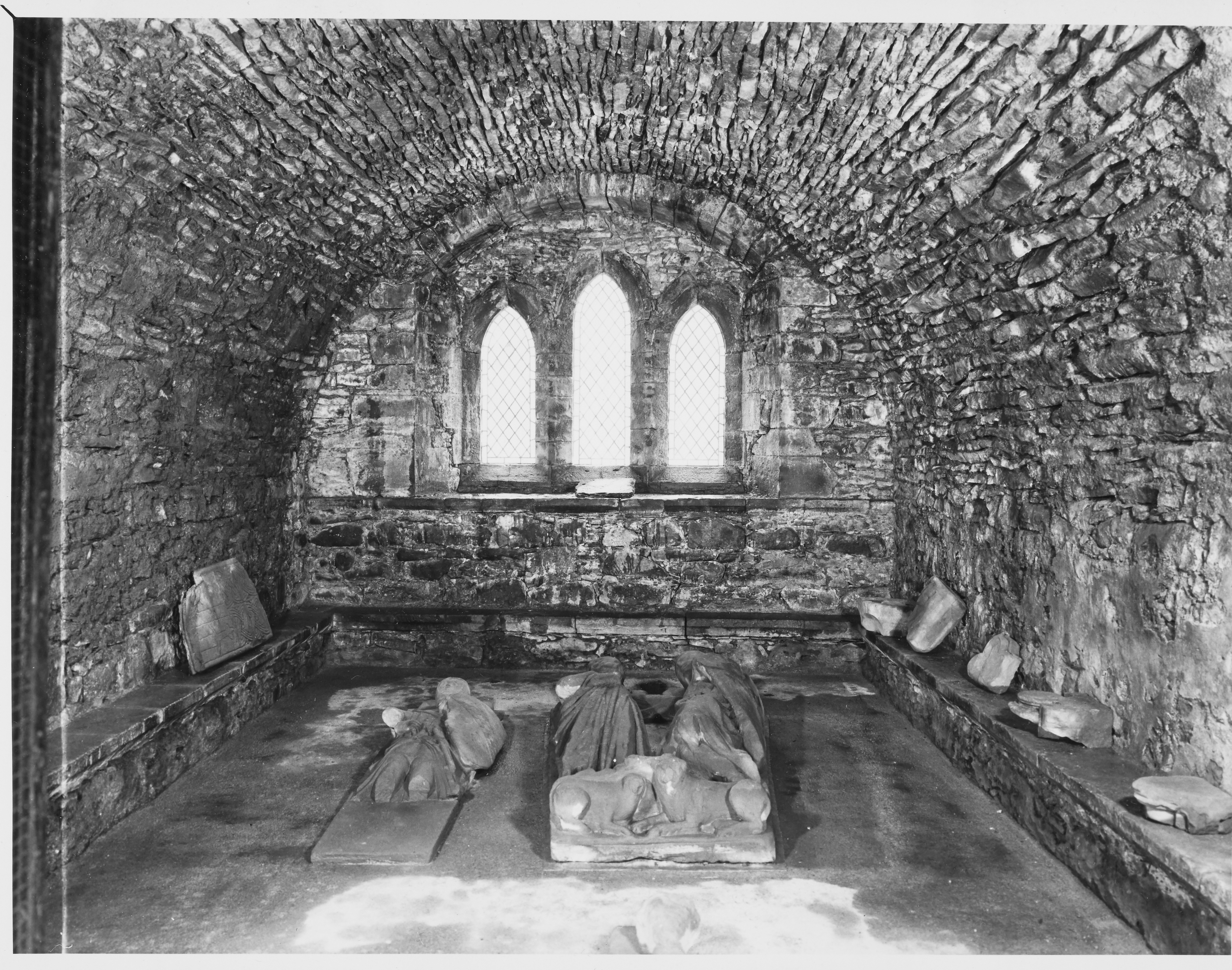 Black and white image inside a priory, with stones around inside a small area with curved roof