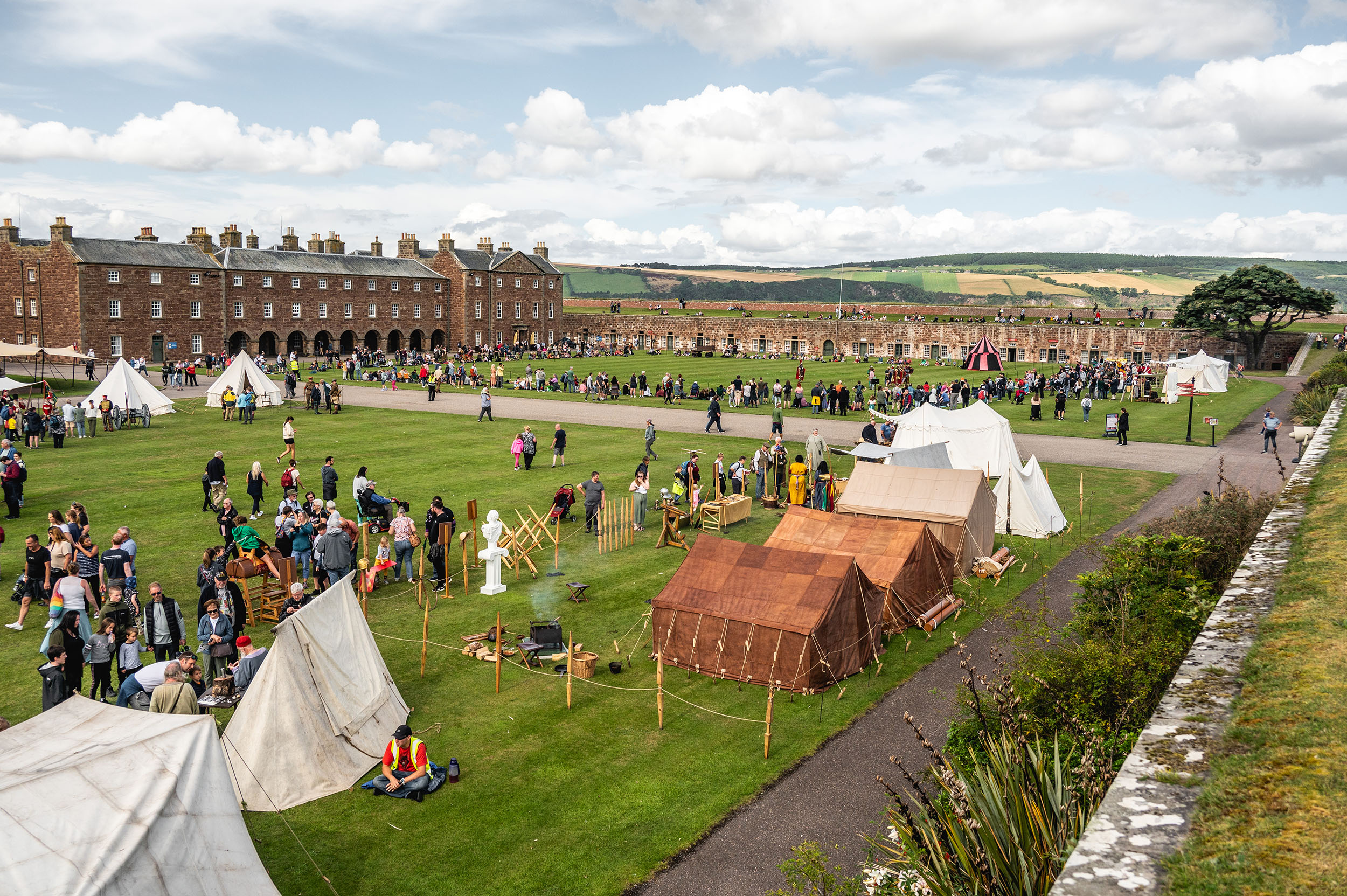 Aerial view of a historic fort with marquees, re-enactors and lots of visitors enjoying an event