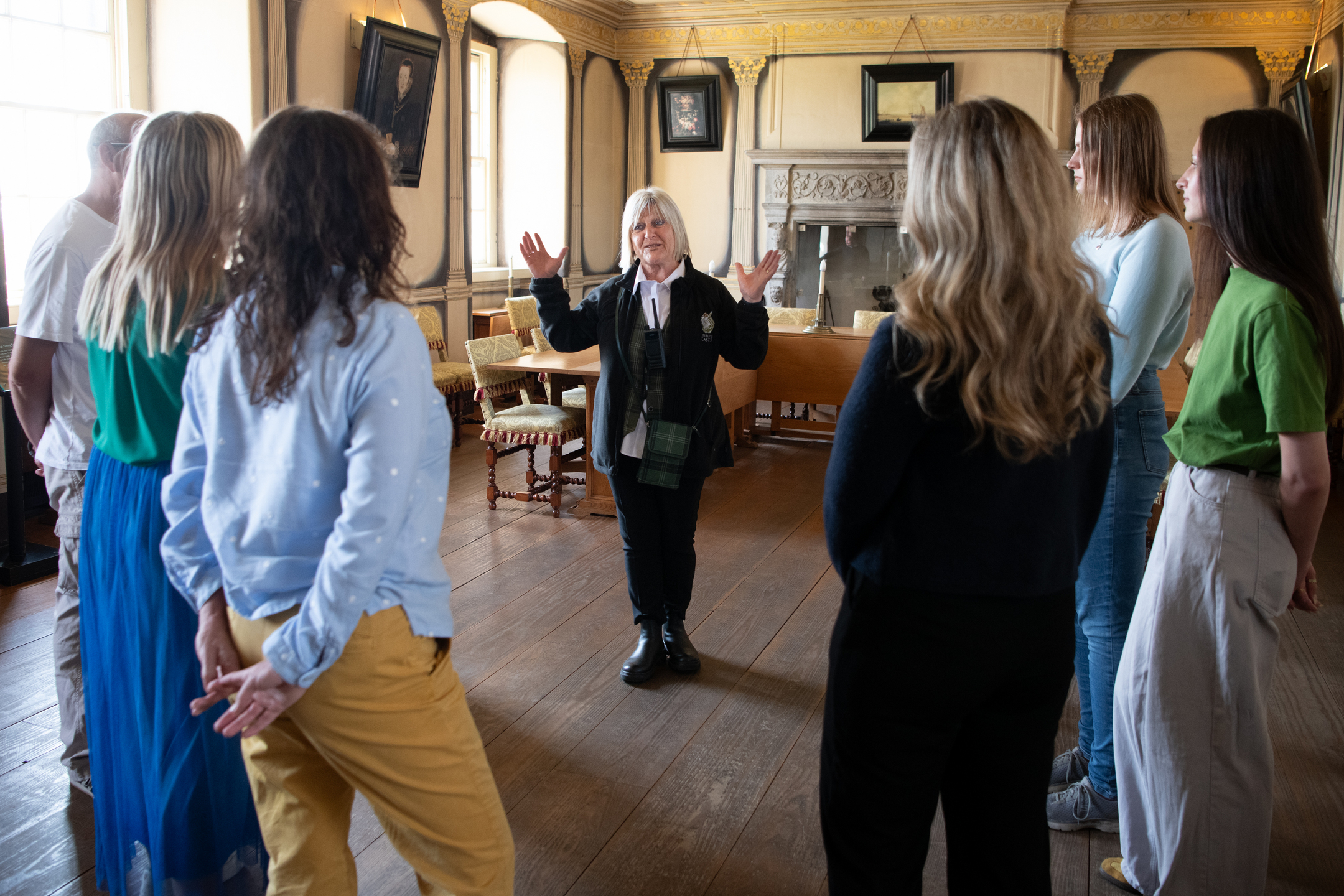 Visitors listening to a tour guide as they explore a historic townhouse.