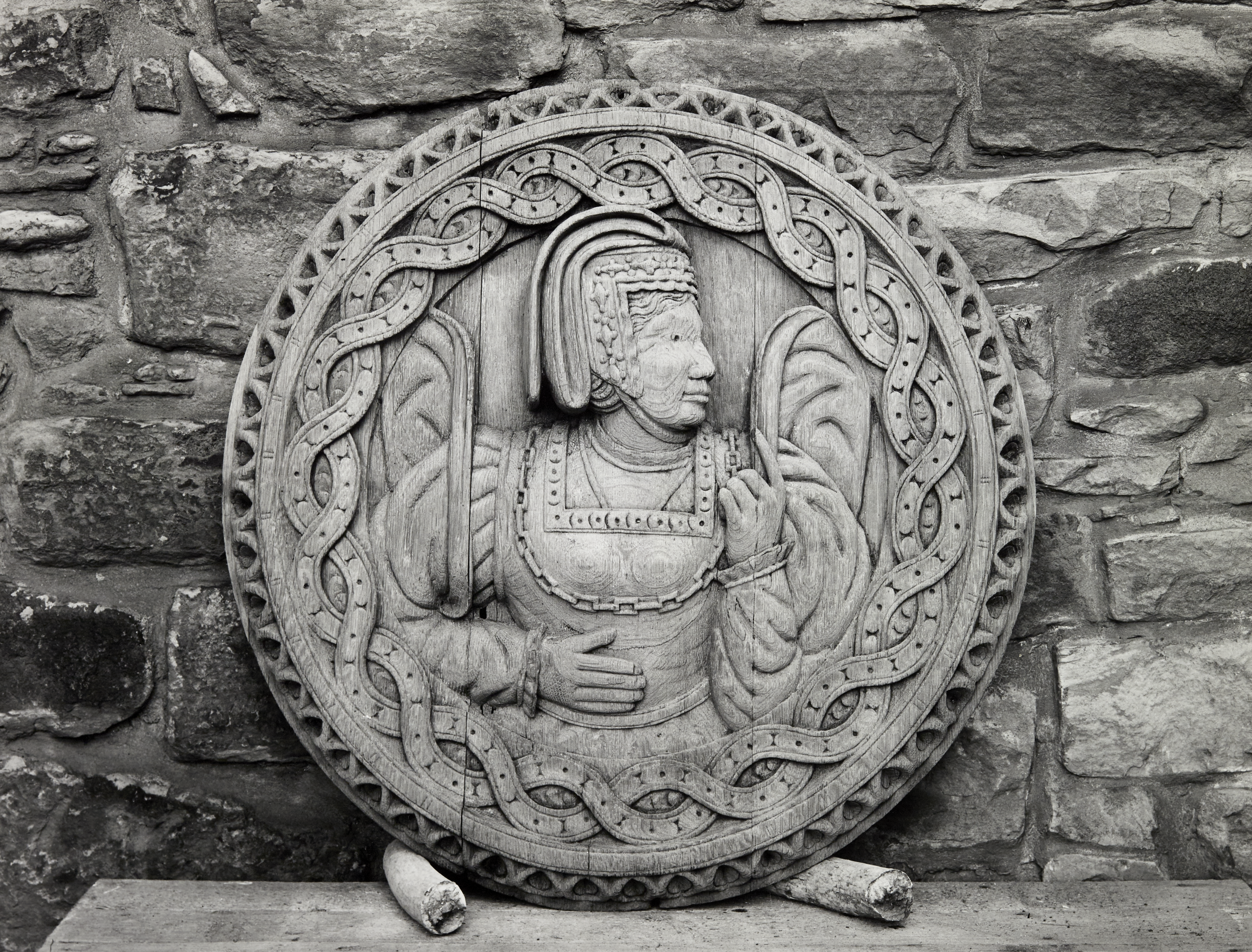Black and white photo of one of the decorative Stirling Heads propped up beside a wall