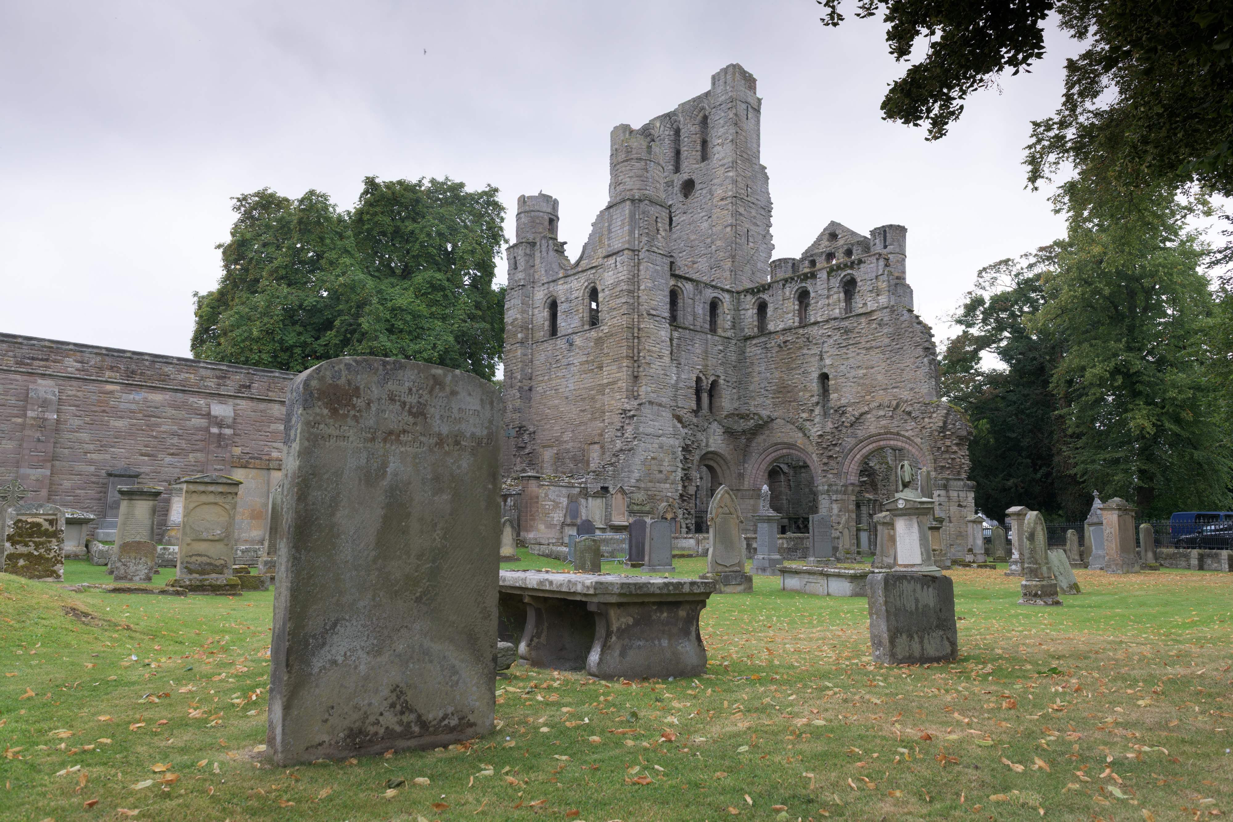 A historic abbey ruin and grassy grounds with many gravestones and memorials