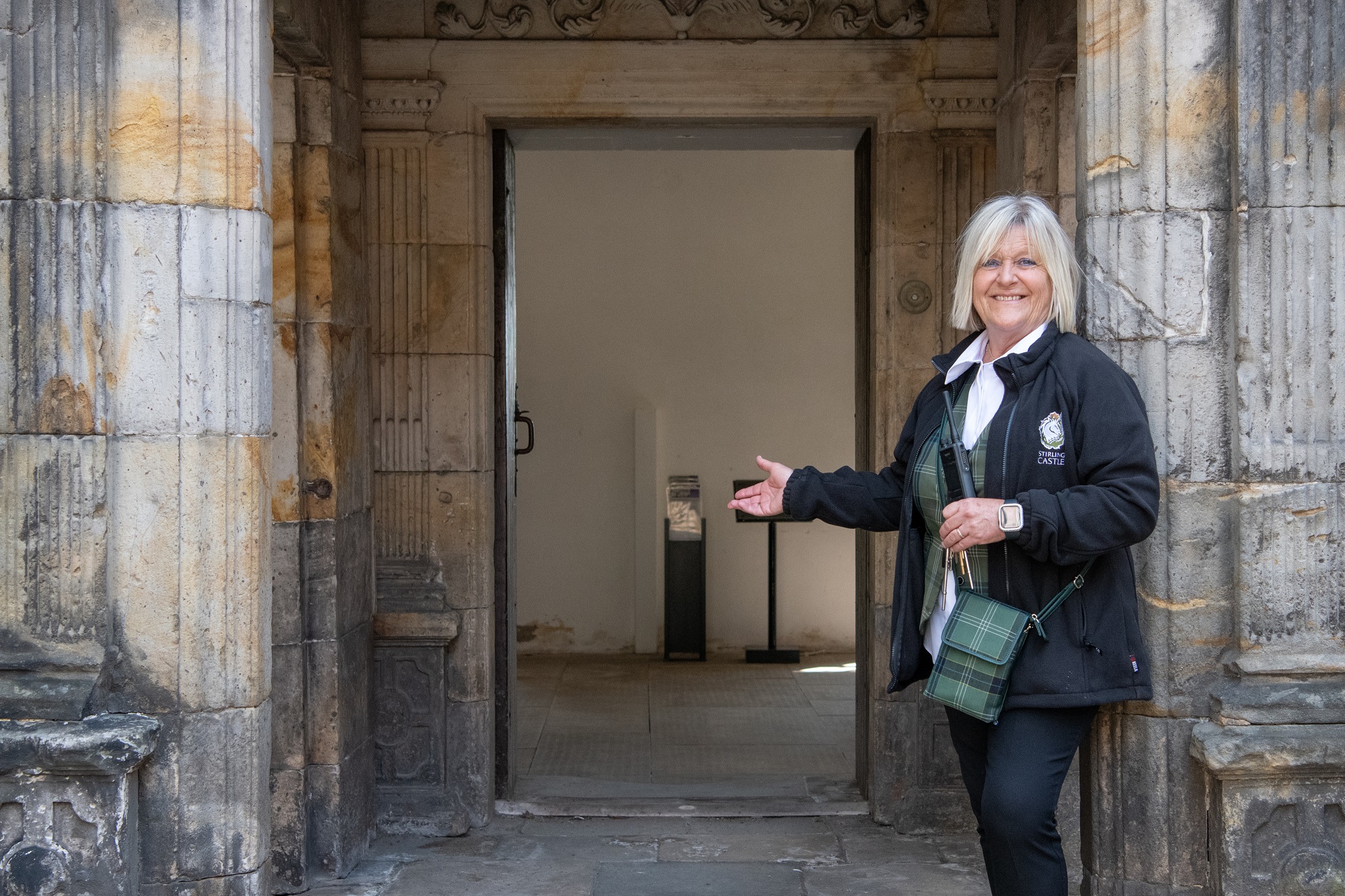 A guide in Stirling Castle uniform poses outside the entrance to a grand townhouse.