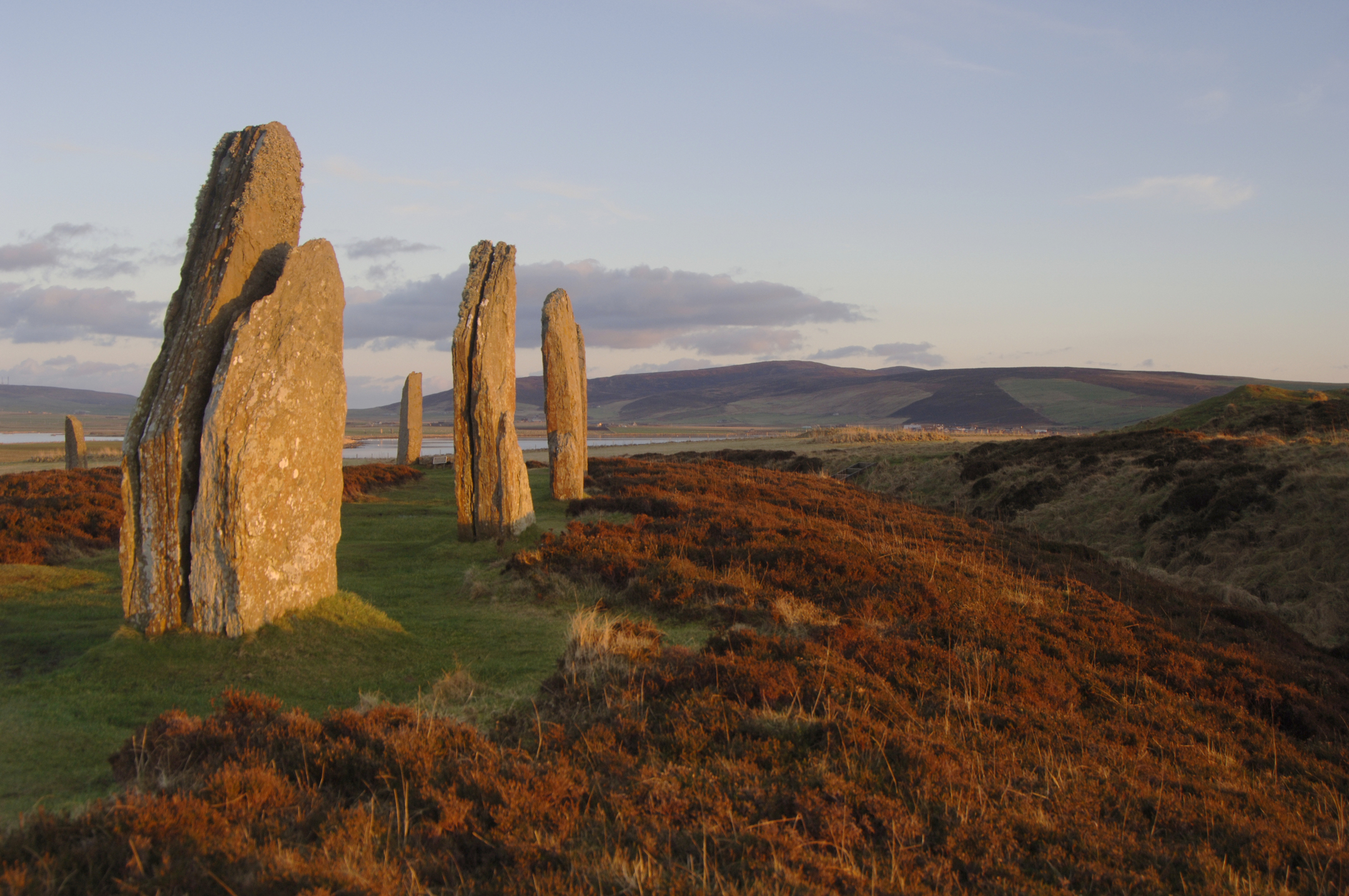 Huge standing stones forming part of a massive stone circle in a bleak yet beautiful landscape dominated by moorland and a loch.