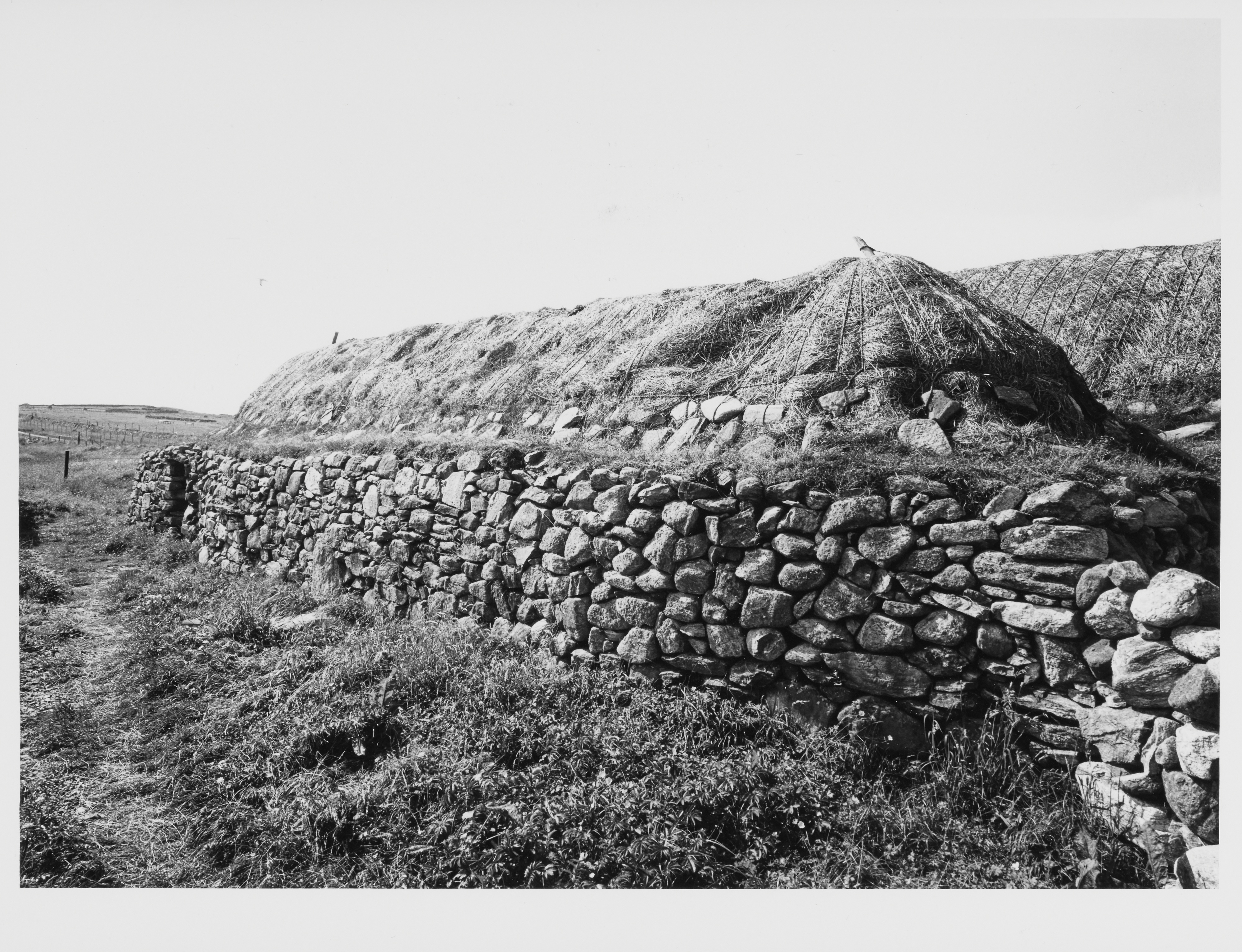 A long, thatched single-storey building with rubble stone walls in the countryside