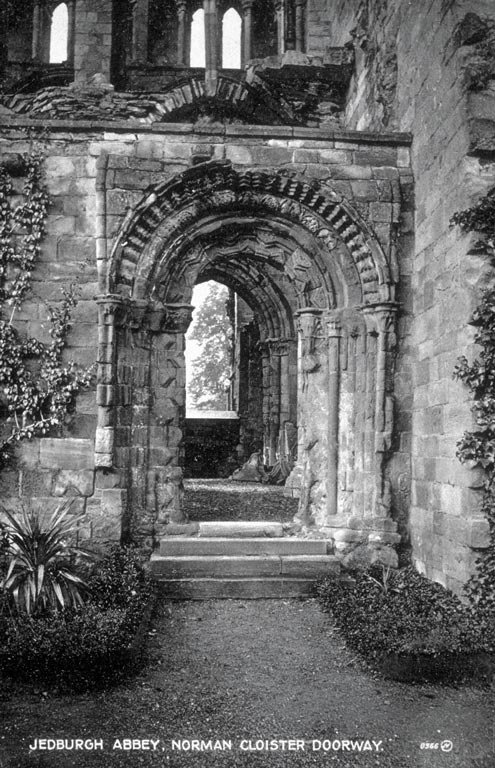 A stone abbey cloister, with decorative archway featuring intricate stone detail