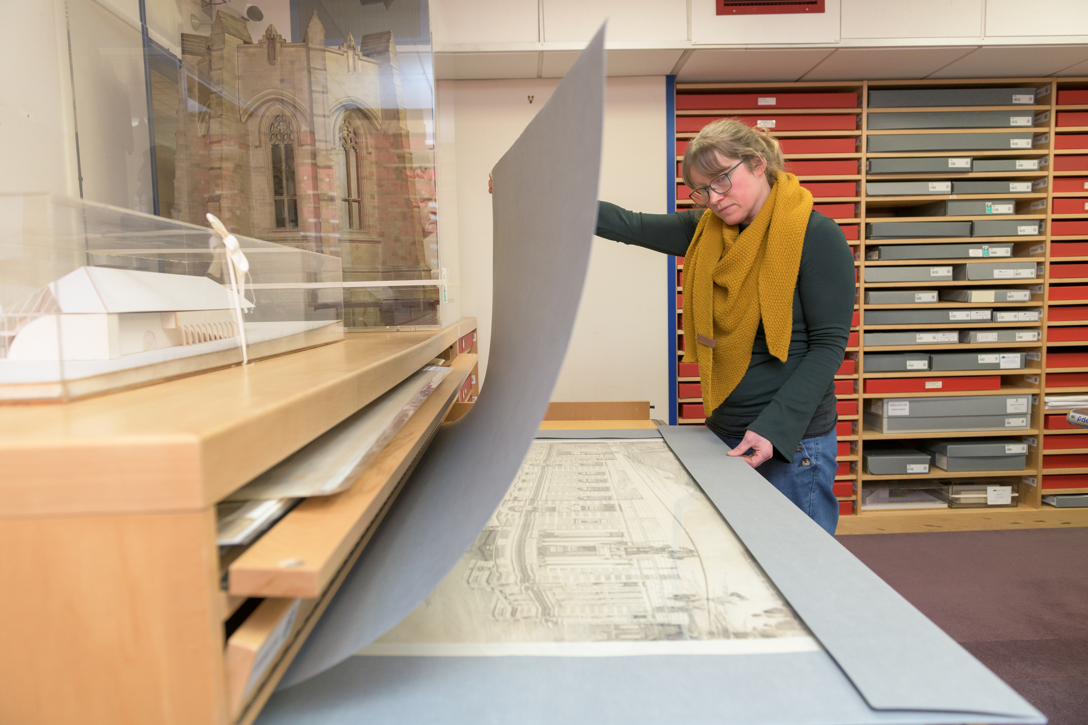 Person holds up a protective cover to see a large drawing underneath