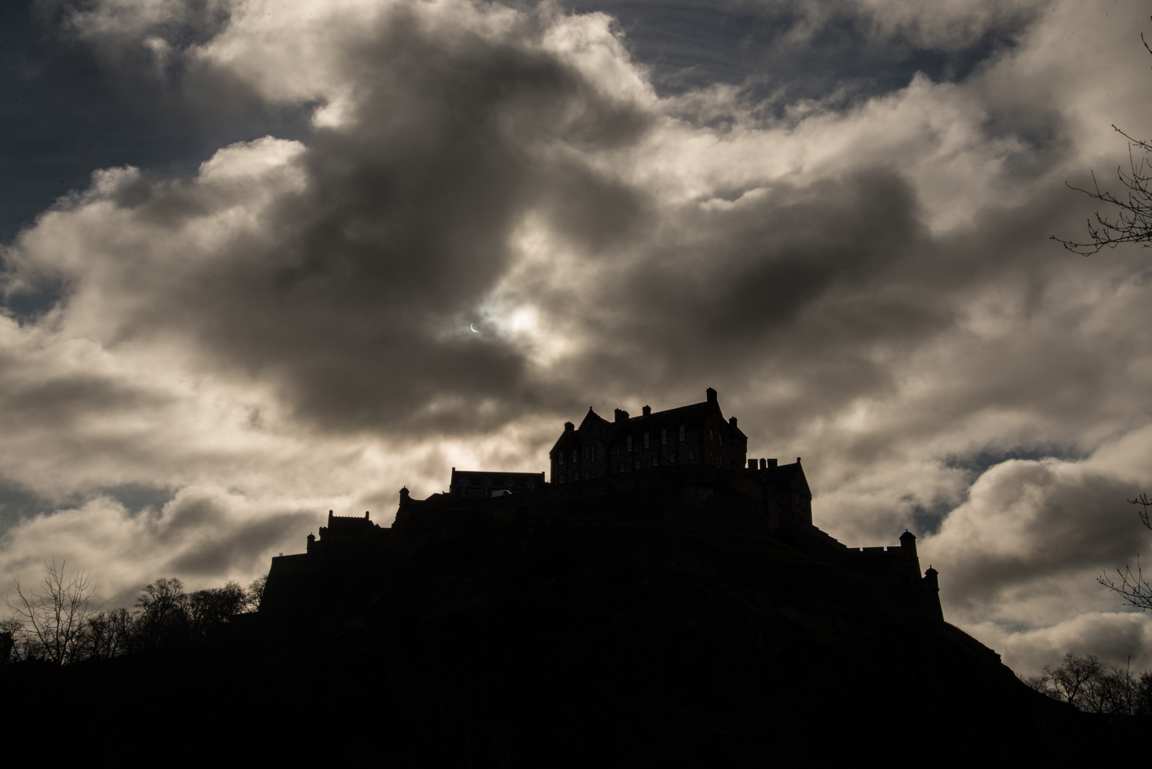 The dark outline of Edinburgh Castle against a grey clouded sky.