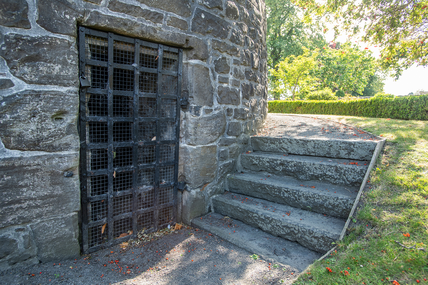 close up of the entrance to a stone building covered over with iron bars, with a small set of steps beside it