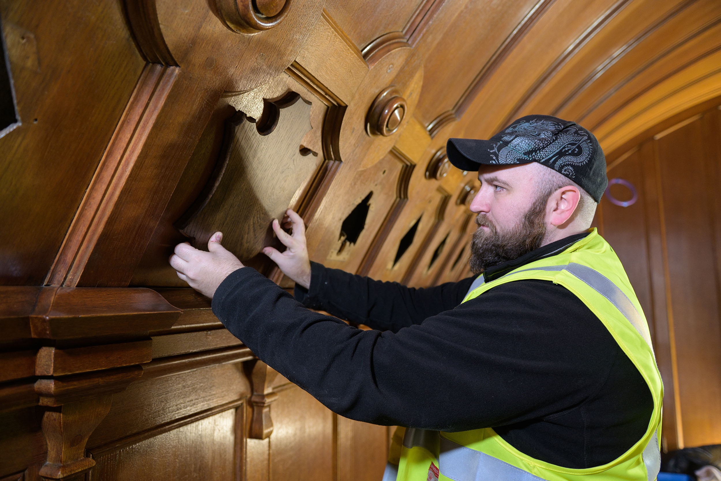 An HES apprentice joiner wearing a high vis jacket and working with wood