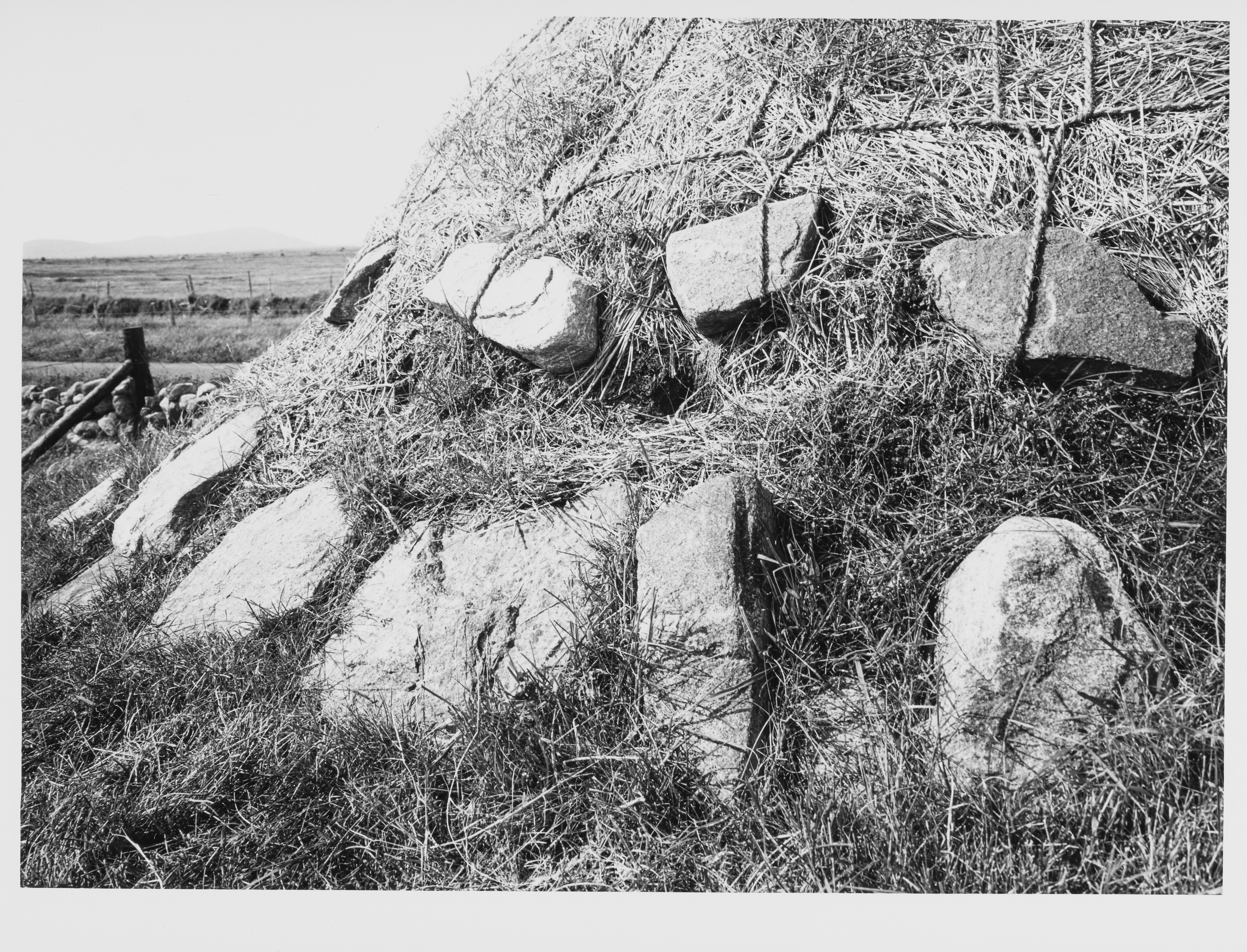 A thatched roof weighed down with ropes and stones 