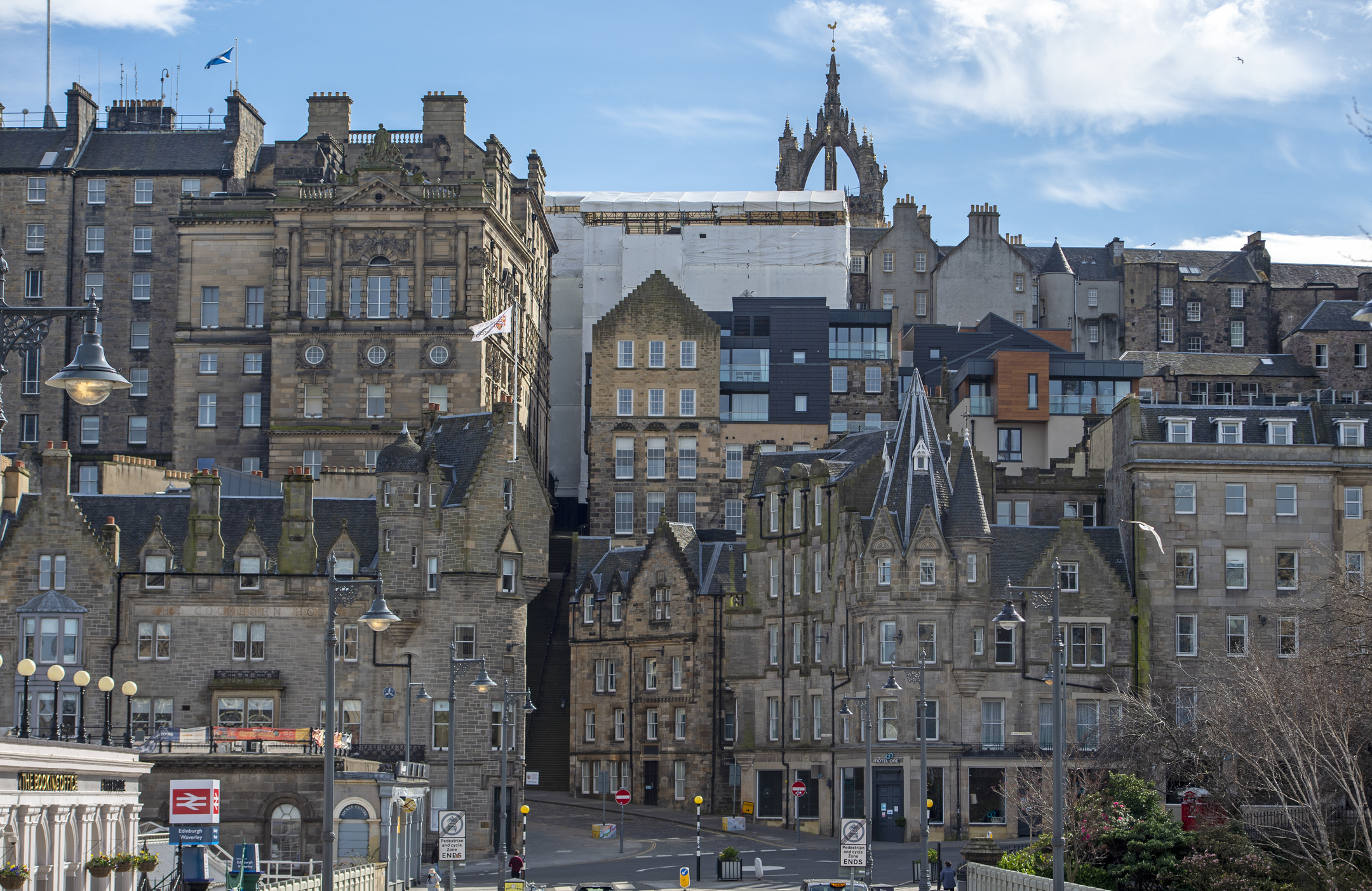 View from a bridge looking towards densely packed historical stone buildings on a hill in Edinburgh