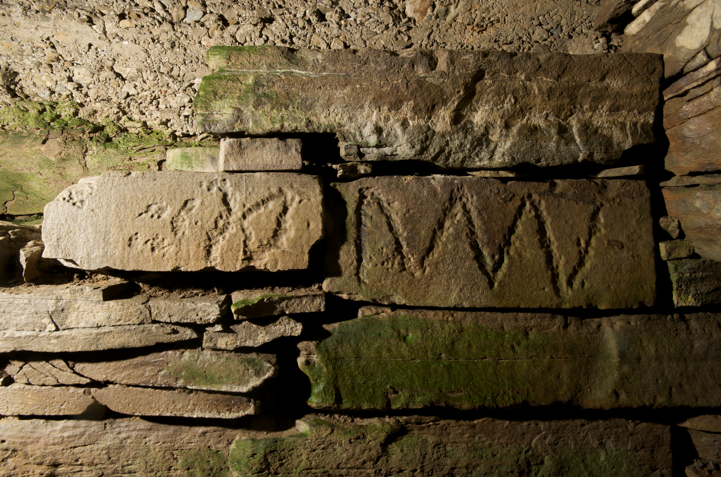 Stone wall, with carving on the side of two of the stones. 