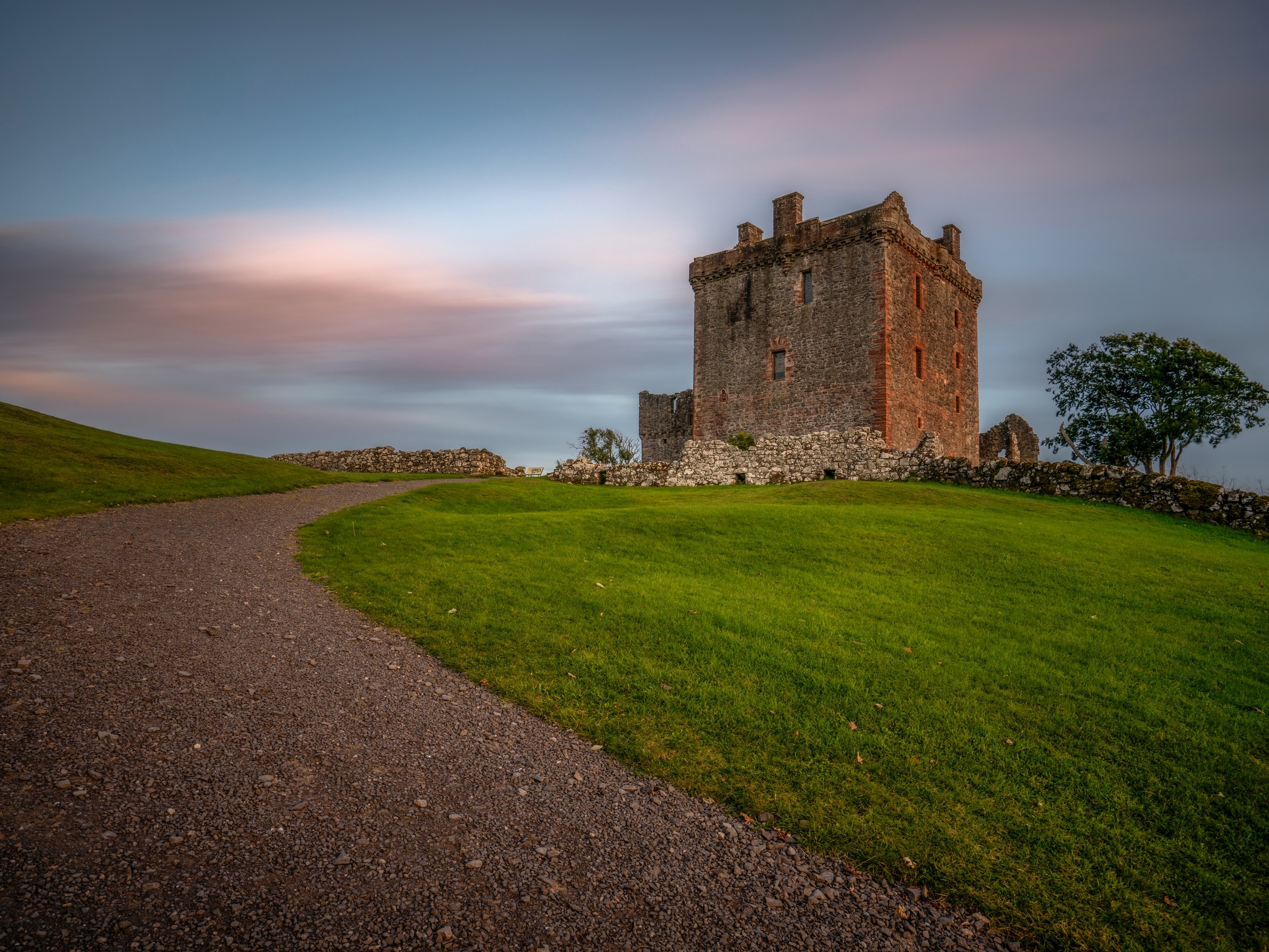 A track curves as it approaches a historic tower house. 
