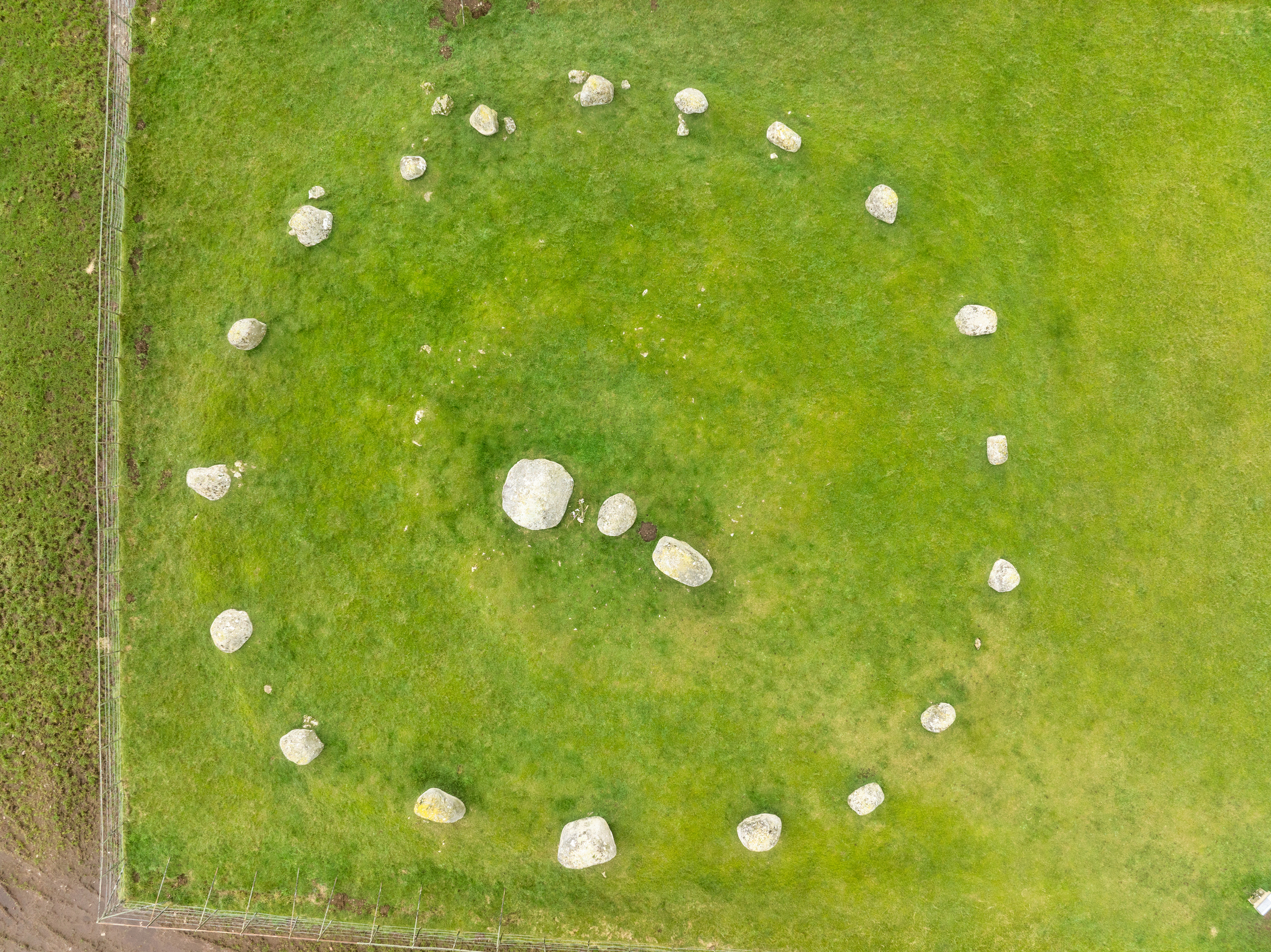Top‑down aerial image of Torhouse Stone Circle displaying its full circular layout of stones on green grass