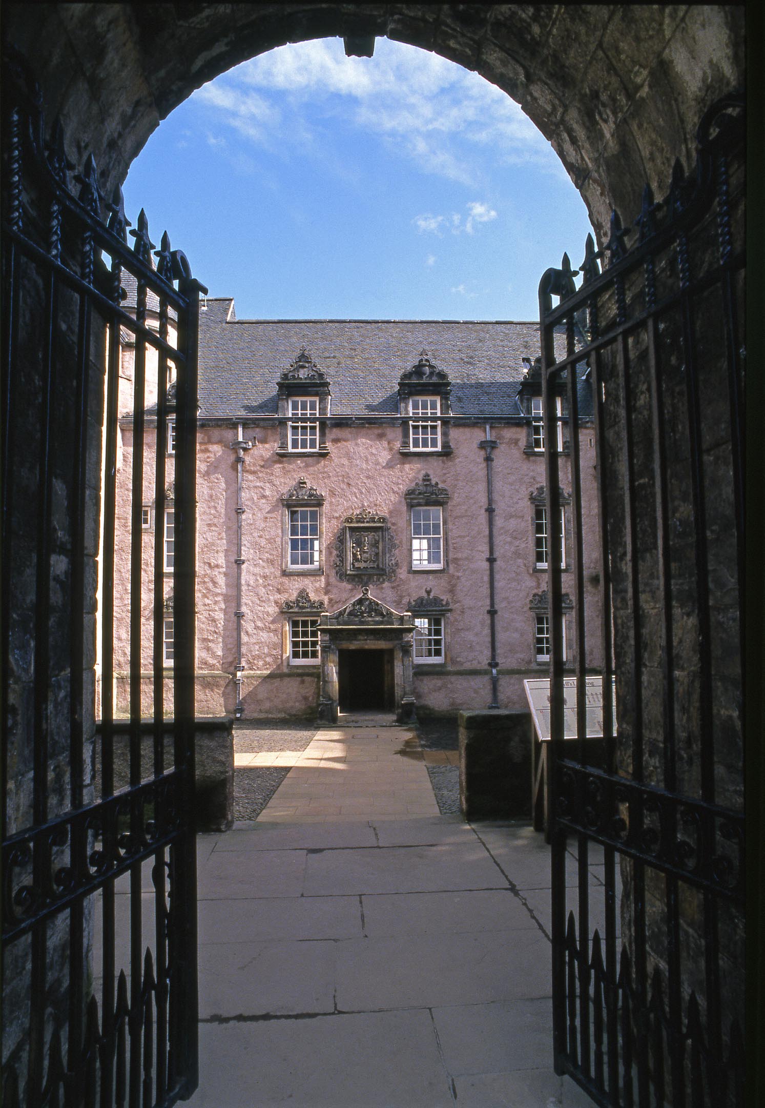 View through archway to courtyard and pink facade of Argyll's Lodging under blue sky.