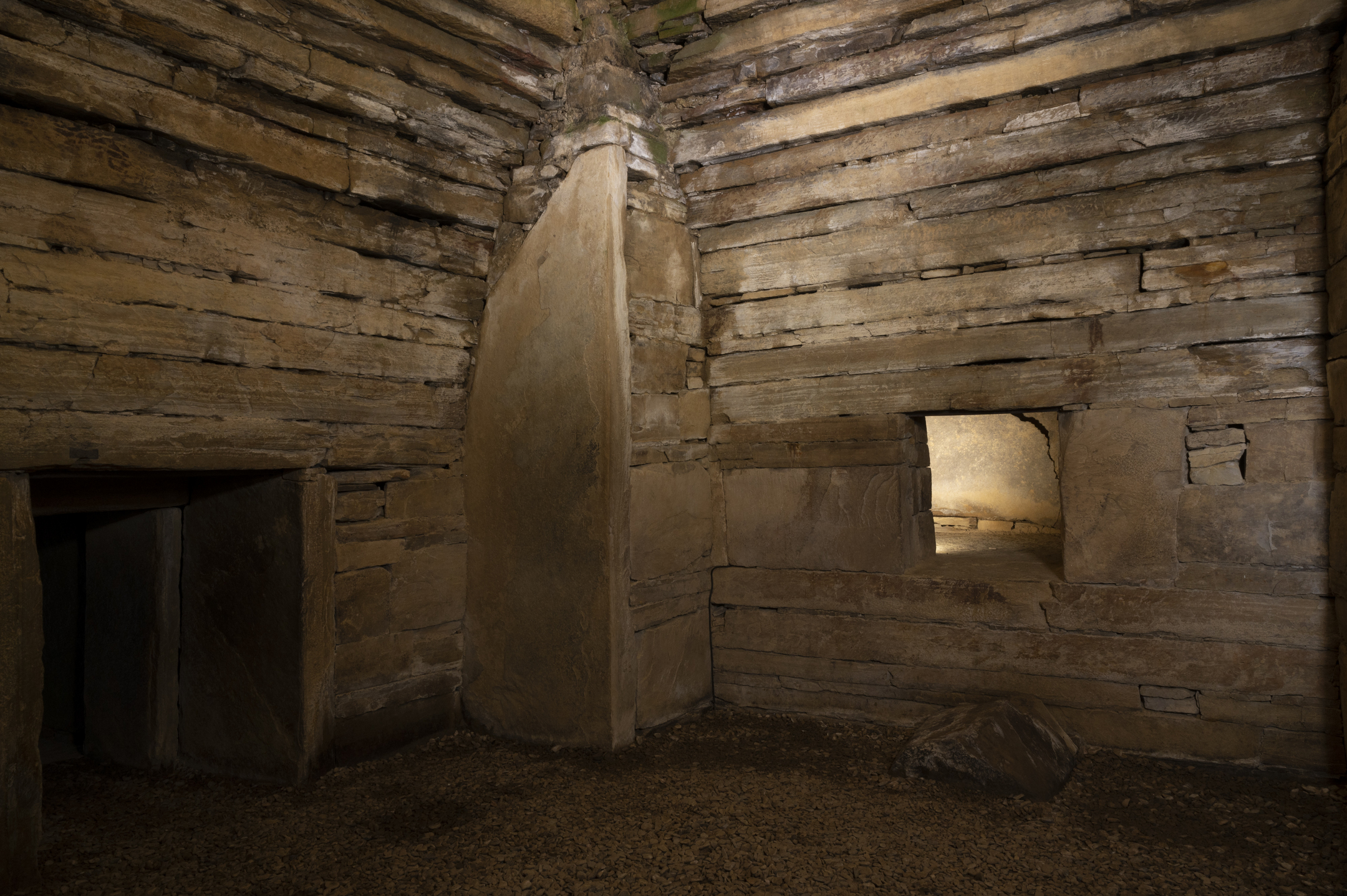 Interior of a stone chambered cairn with rough-hewn stone walls.