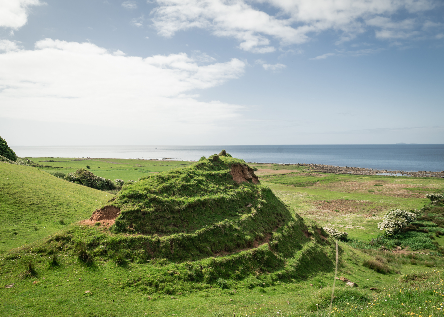 A mound with circular ridged edges, with the sea in the background.